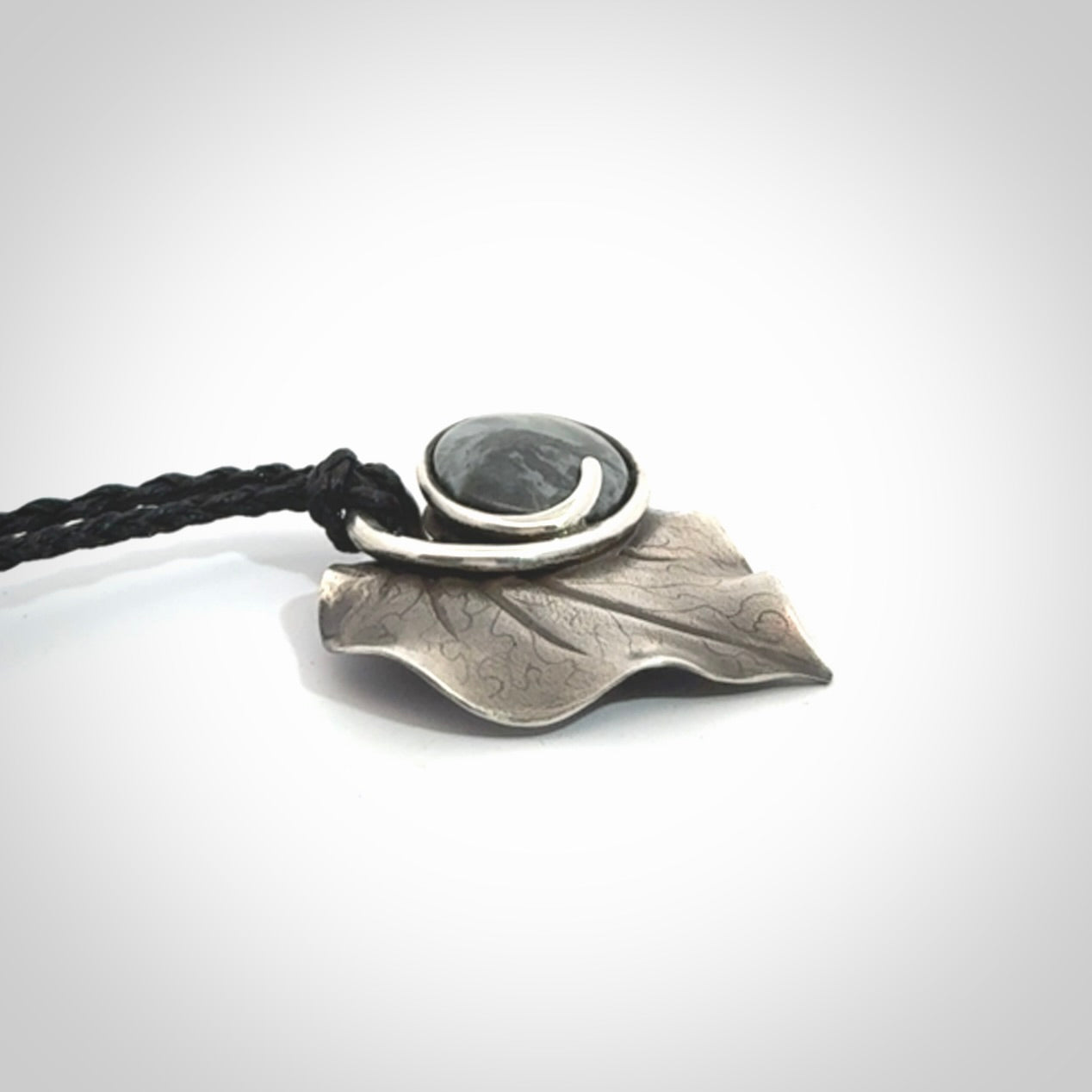 This is a hand carved Sterling Silver Kawakawa leaf pendant with New Zealand Jade insert. This is a medium sized necklace and is provided with an adjustable black cord.