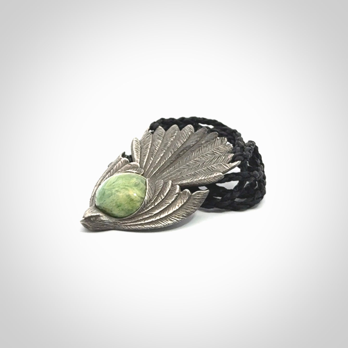 This is a hand carved Sterling Silver Fern fantail pendant with New Zealand Jade insert. This is a medium sized necklace and is provided with an adjustable black cord.