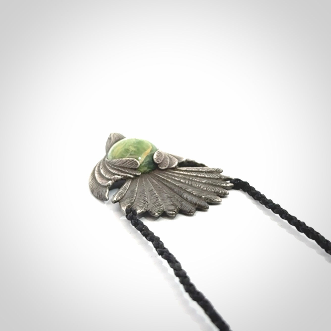 This is a hand carved Sterling Silver Fern fantail pendant with New Zealand Jade insert. This is a medium sized necklace and is provided with an adjustable black cord.