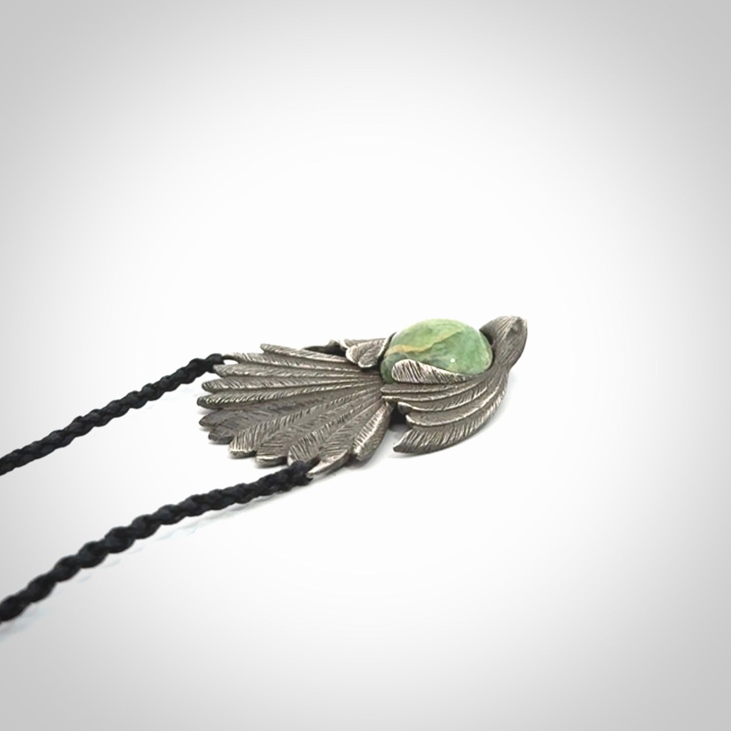 This is a hand carved Sterling Silver Fern fantail pendant with New Zealand Jade insert. This is a medium sized necklace and is provided with an adjustable black cord.