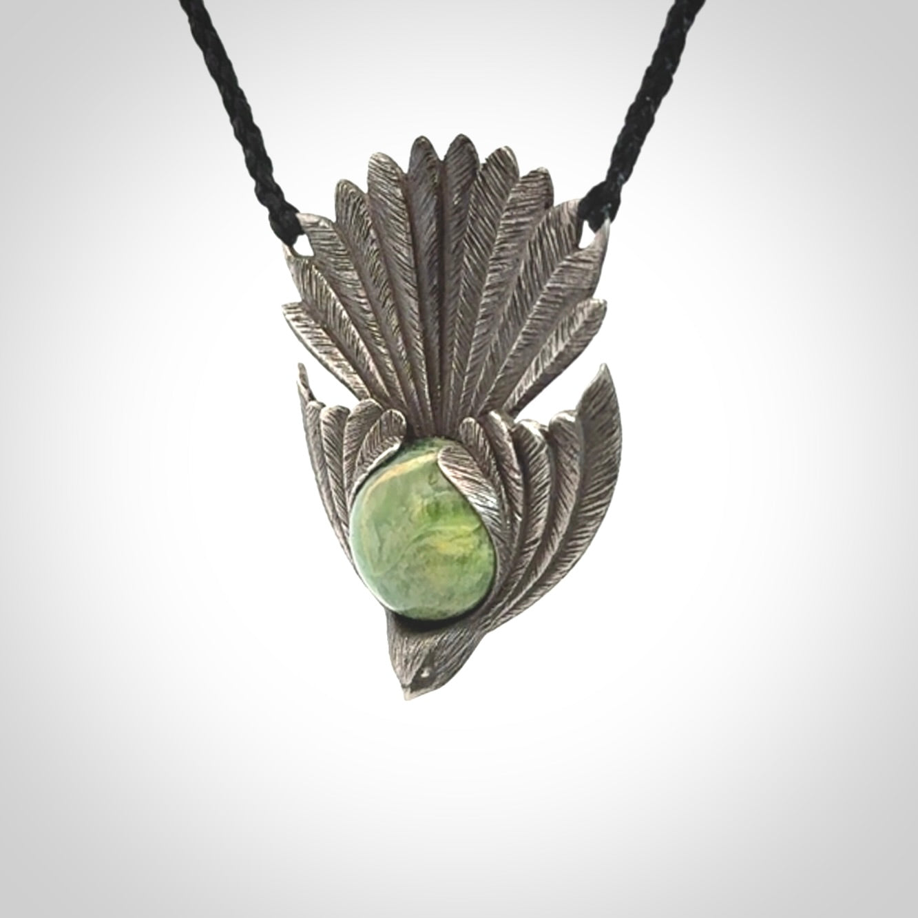 This is a hand carved Sterling Silver Fern fantail pendant with New Zealand Jade insert. This is a medium sized necklace and is provided with an adjustable black cord.