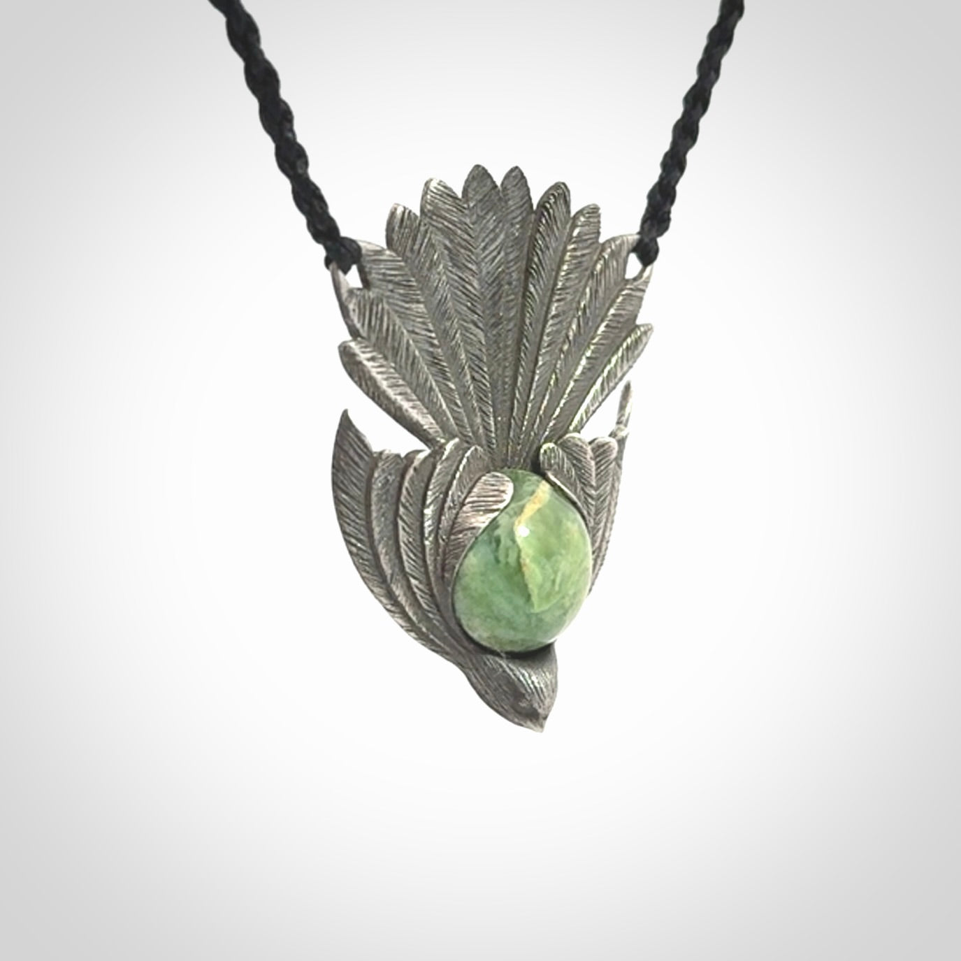 This is a hand carved Sterling Silver Fern fantail pendant with New Zealand Jade insert. This is a medium sized necklace and is provided with an adjustable black cord.