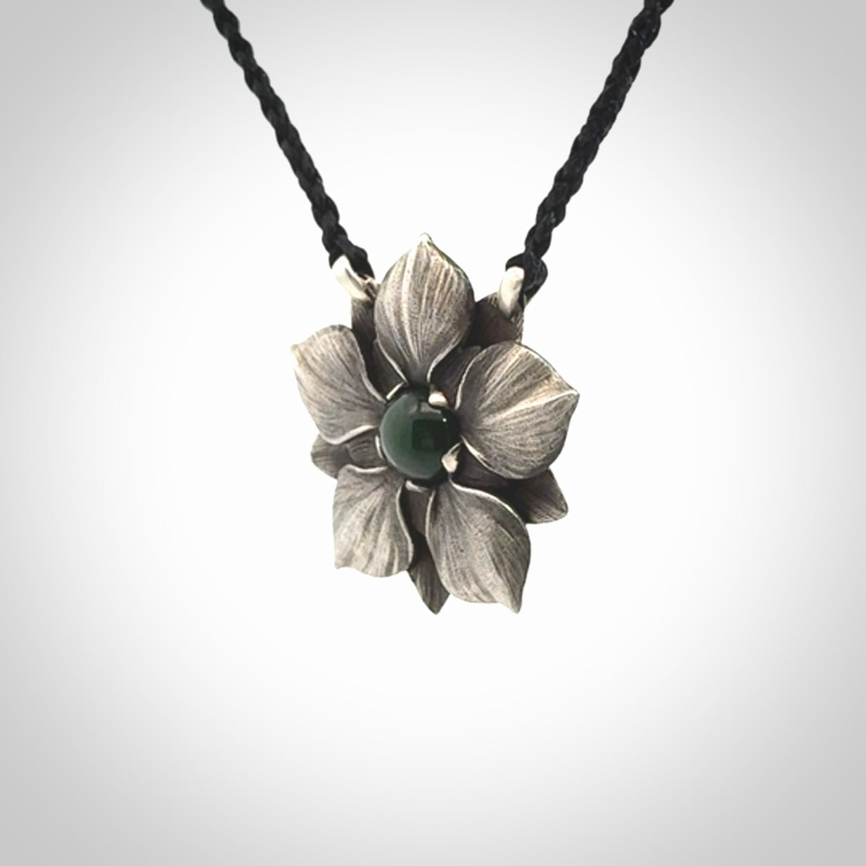 This is a hand carved Sterling Silver Manuka Flower pendant with New Zealand Jade insert. This is a medium sized necklace and is provided with an adjustable black cord.