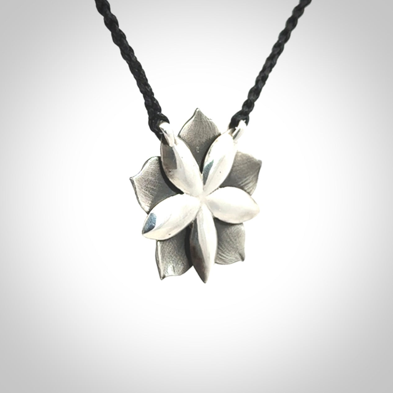 This is a hand carved Sterling Silver Manuka Flower pendant with New Zealand Jade insert. This is a medium sized necklace and is provided with an adjustable black cord.