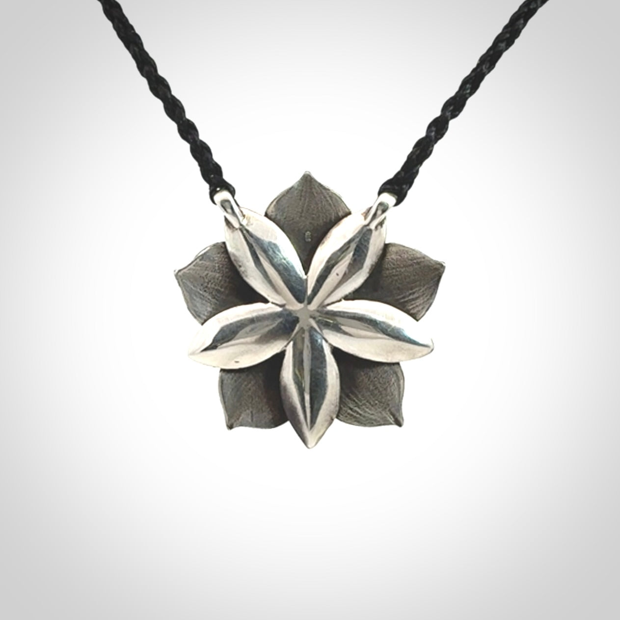 This is a hand carved Sterling Silver Manuka Flower pendant with New Zealand Jade insert. This is a medium sized necklace and is provided with an adjustable black cord.