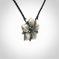 This is a hand carved Sterling Silver Manuka Flower pendant with New Zealand Jade insert. This is a medium sized necklace and is provided with an adjustable black cord.