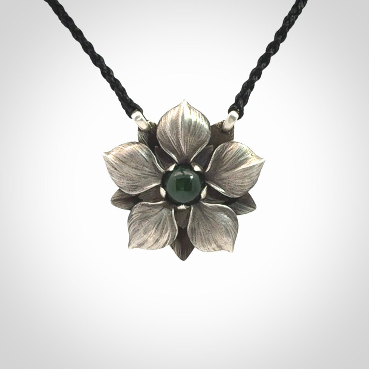 This is a hand carved Sterling Silver Manuka Flower pendant with New Zealand Jade insert. This is a medium sized necklace and is provided with an adjustable black cord.