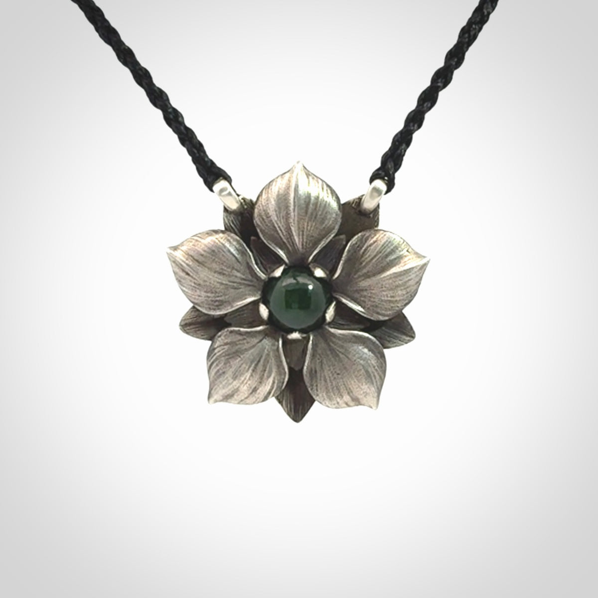 This is a hand carved Sterling Silver Manuka Flower pendant with New Zealand Jade insert. This is a medium sized necklace and is provided with an adjustable black cord.