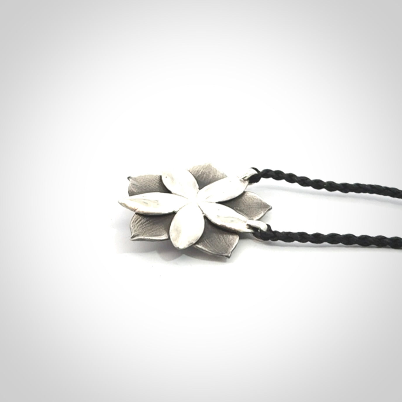 This is a hand carved Sterling Silver Manuka Flower pendant with New Zealand Jade insert. This is a medium sized necklace and is provided with an adjustable black cord.