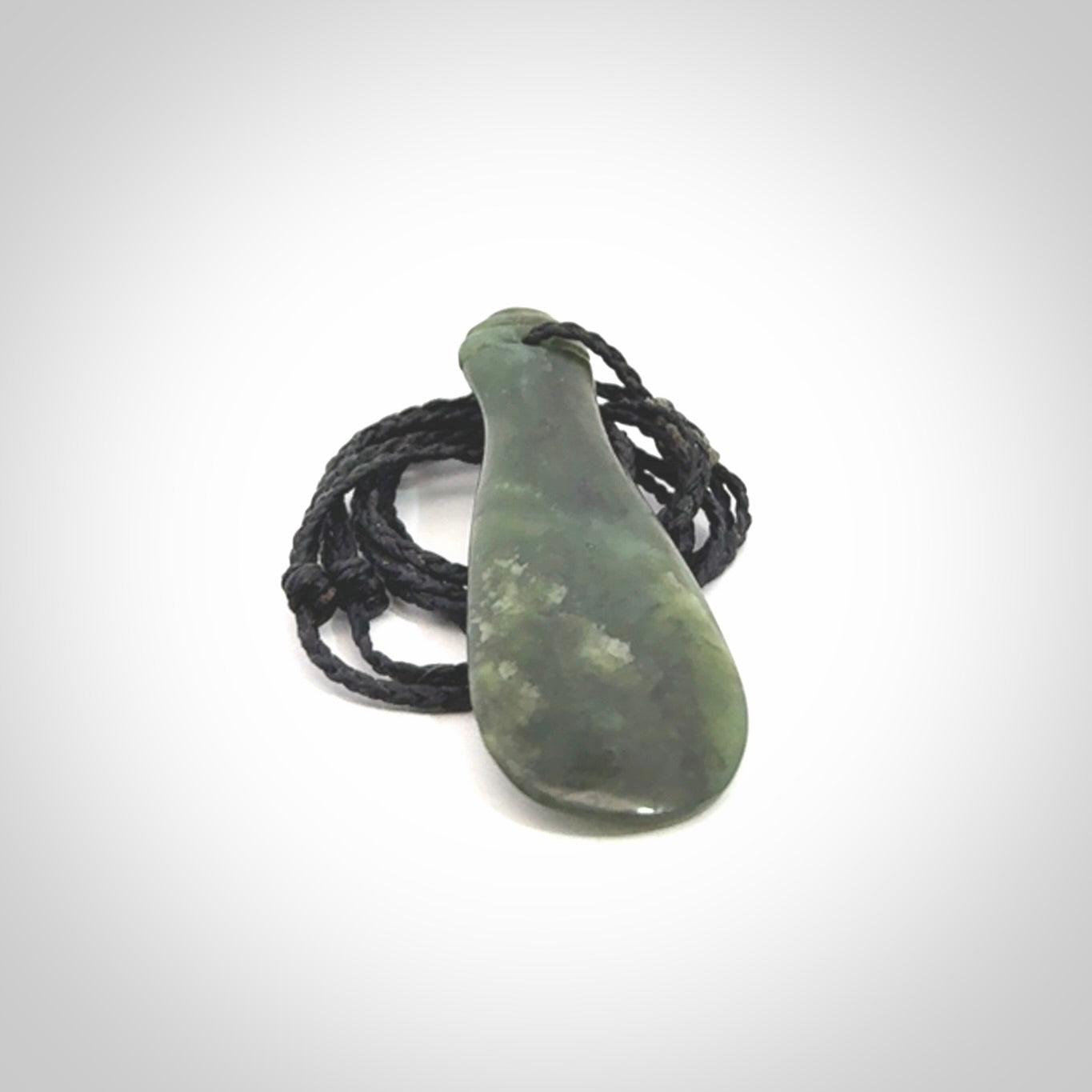 This is a sleek and slender hand carved New Zealand Jade mere pendant. The stone is a very beautiful green and the cord is either black, red or grey and is adjustable. The pendant has a light polish and just glows. Provided in a woven kete pouch.