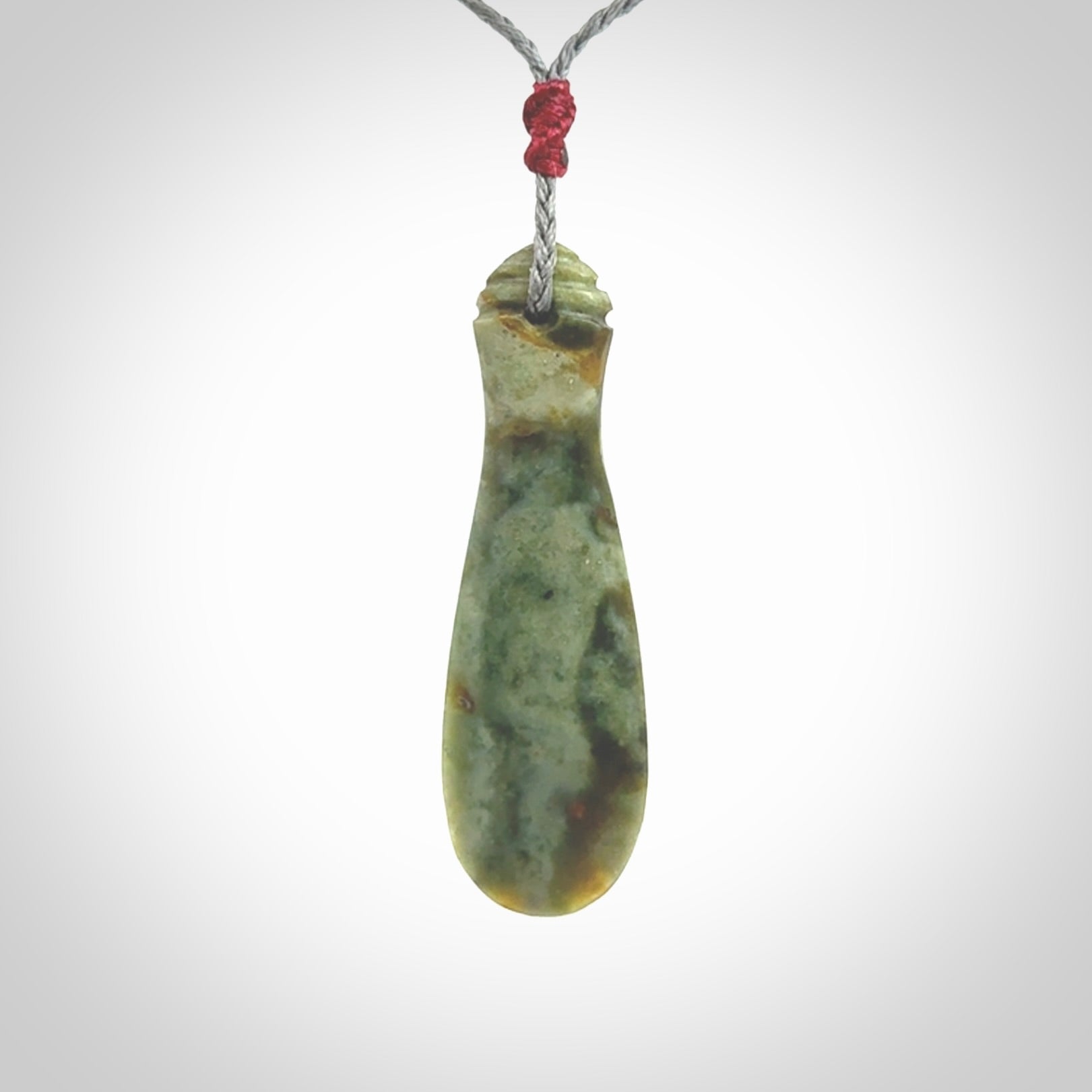 This is a sleek and slender hand carved New Zealand Jade mere pendant. The stone is a very beautiful green and the cord is either black, red or grey and is adjustable. The pendant has a light polish and just glows. Provided in a woven kete pouch.