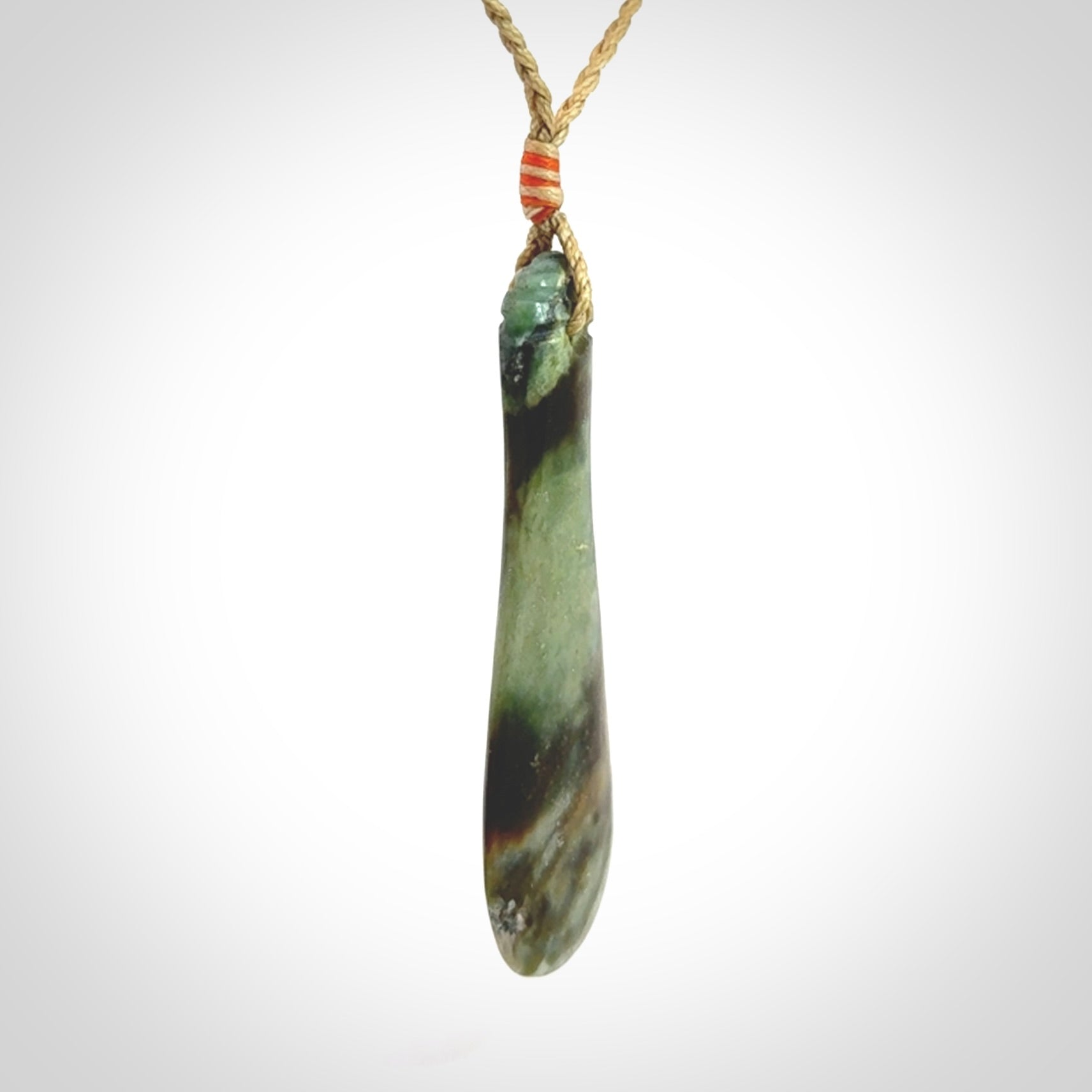 This is a sleek and slender hand carved New Zealand Jade mere pendant. The stone is a very beautiful green and the cord is tan and is adjustable. The pendant has a light polish and just glows. Provided in a woven kete pouch.