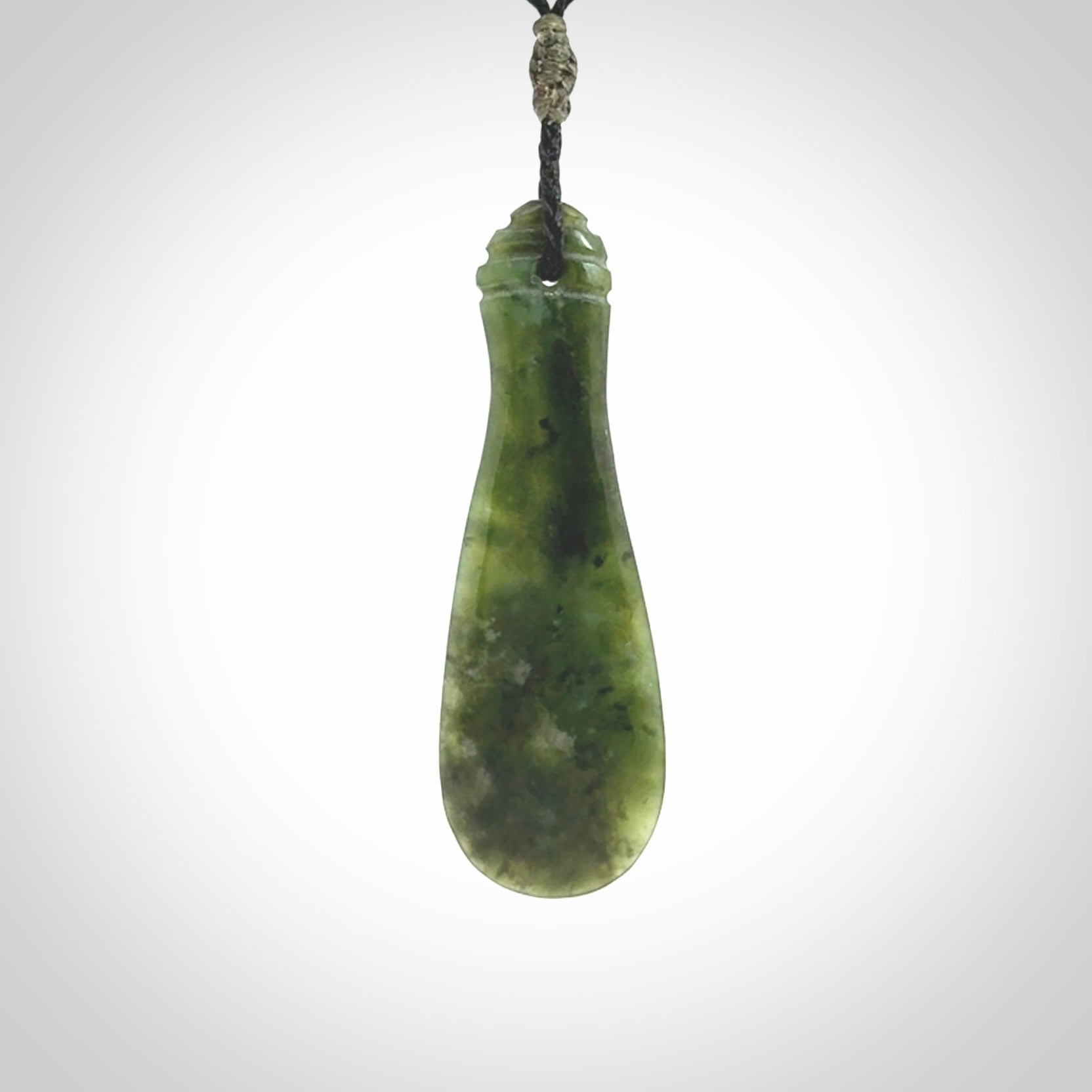 This is a sleek and slender hand carved New Zealand Jade mere pendant. The stone is a very beautiful green and the cord is either black, red or grey and is adjustable. The pendant has a light polish and just glows. Provided in a woven kete pouch.