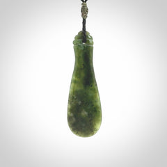 This is a sleek and slender hand carved New Zealand Jade mere pendant. The stone is a very beautiful green and the cord is either black, red or grey and is adjustable. The pendant has a light polish and just glows. Provided in a woven kete pouch.