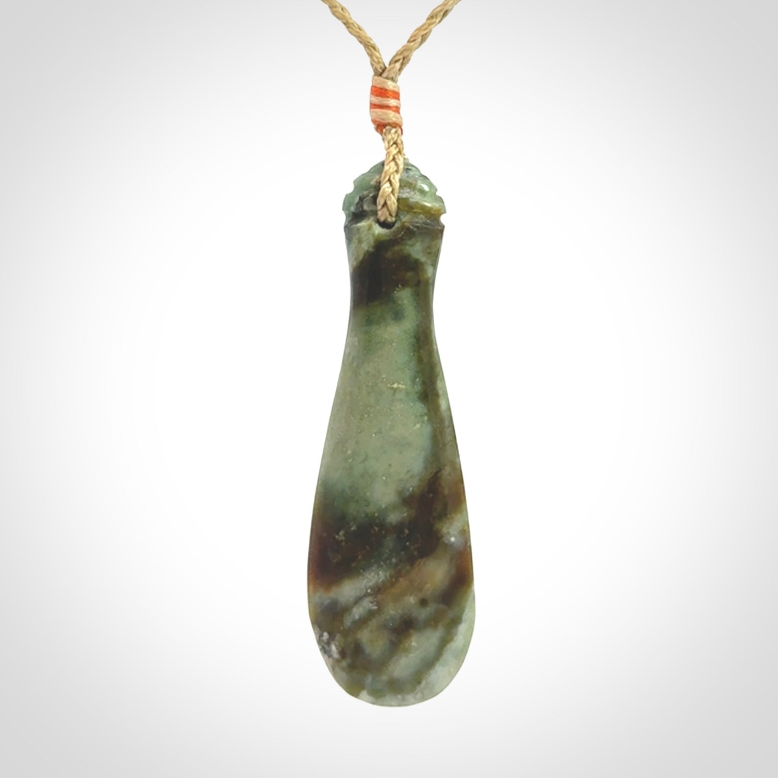 This is a sleek and slender hand carved New Zealand Jade mere pendant. The stone is a very beautiful green and the cord is tan and is adjustable. The pendant has a light polish and just glows. Provided in a woven kete pouch.