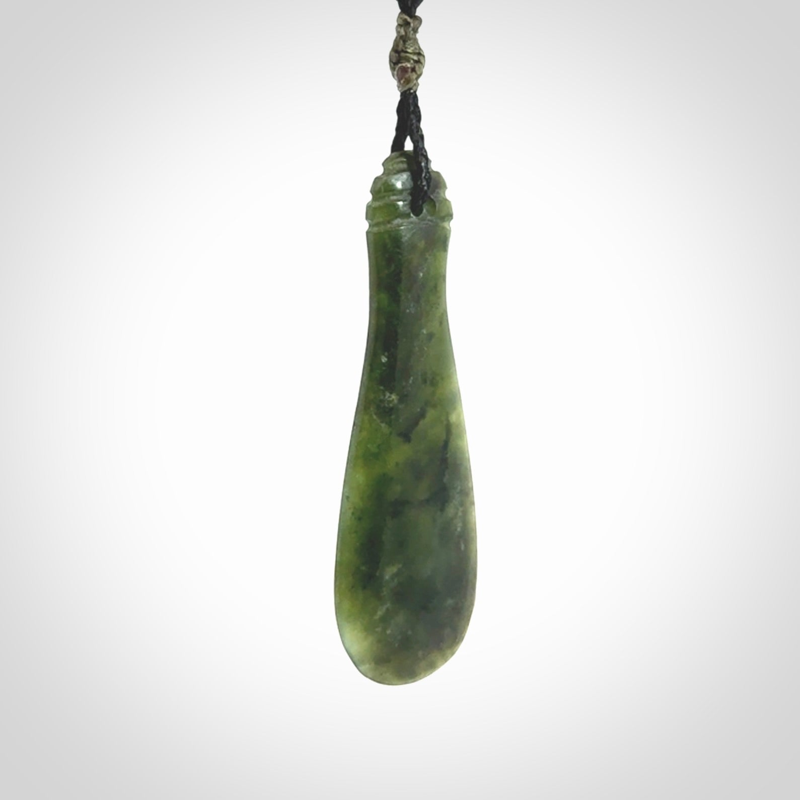 This is a sleek and slender hand carved New Zealand Jade mere pendant. The stone is a very beautiful green and the cord is either black, red or grey and is adjustable. The pendant has a light polish and just glows. Provided in a woven kete pouch.