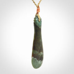 This is a sleek and slender hand carved New Zealand Jade mere pendant. The stone is a very beautiful green and the cord is tan and is adjustable. The pendant has a light polish and just glows. Provided in a woven kete pouch.
