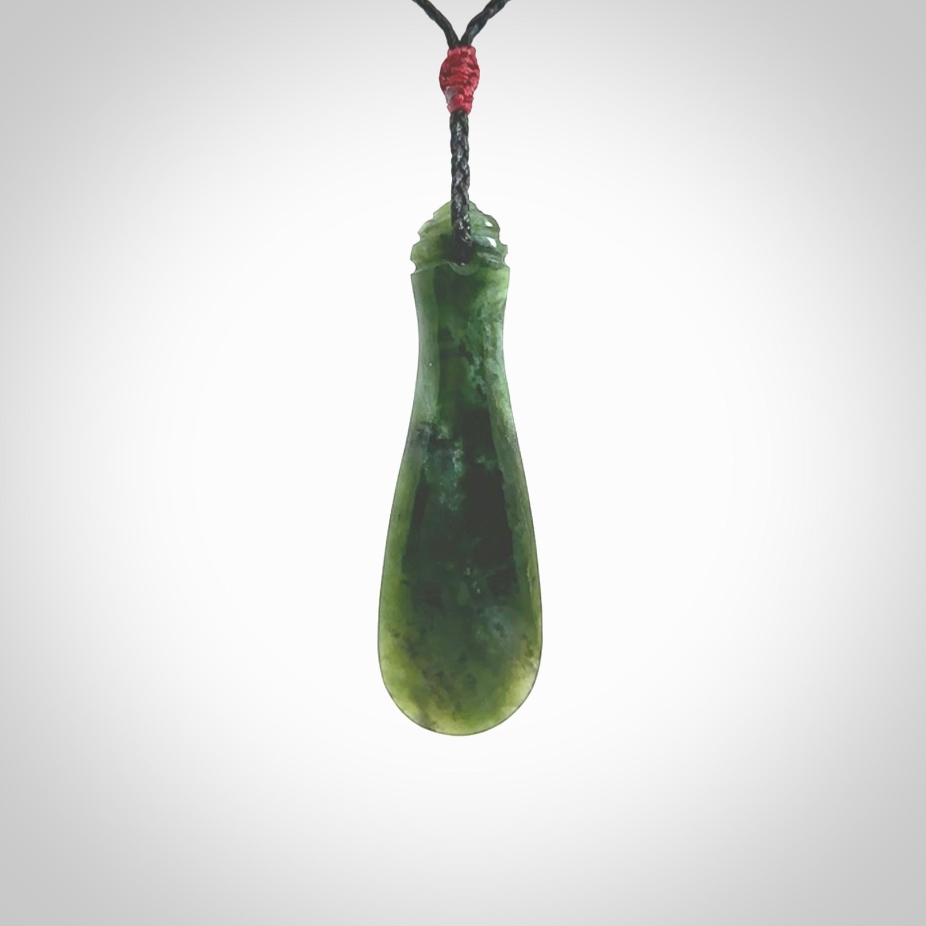 This is a sleek and slender hand carved New Zealand Jade mere pendant. The stone is a very beautiful green and the cord is either black, red or green and is adjustable. The pendant has a light polish and just glows. Provided in a woven kete pouch.