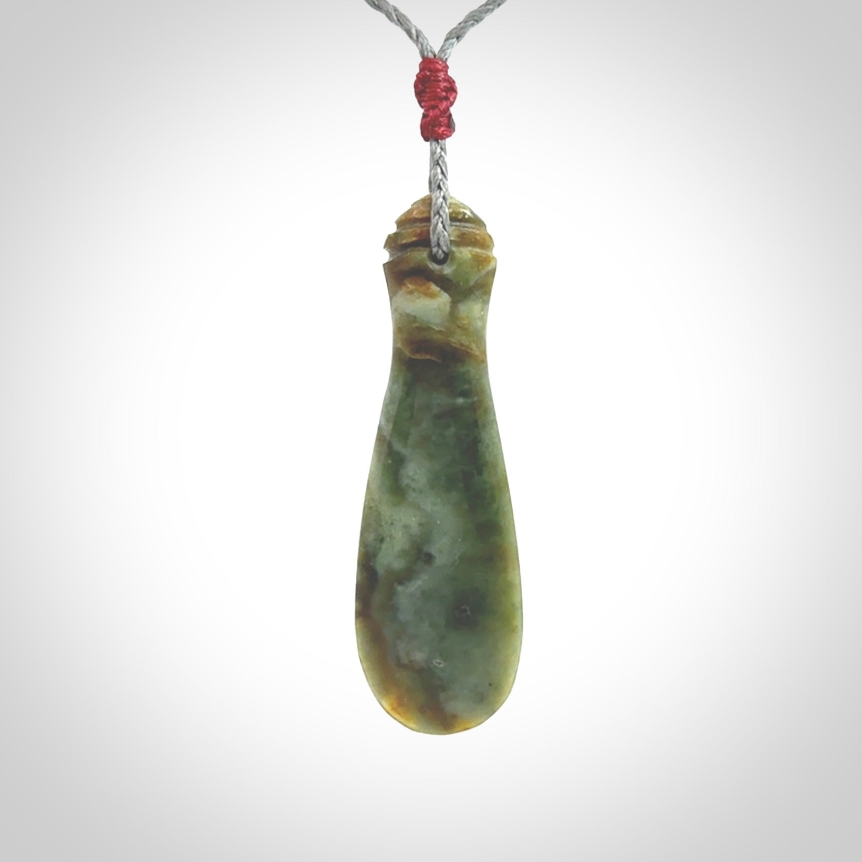 This is a sleek and slender hand carved New Zealand Jade mere pendant. The stone is a very beautiful green and the cord is either black, red or grey and is adjustable. The pendant has a light polish and just glows. Provided in a woven kete pouch.