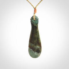 This is a sleek and slender hand carved New Zealand Jade mere pendant. The stone is a very beautiful green and the cord is tan and is adjustable. The pendant has a light polish and just glows. Provided in a woven kete pouch.
