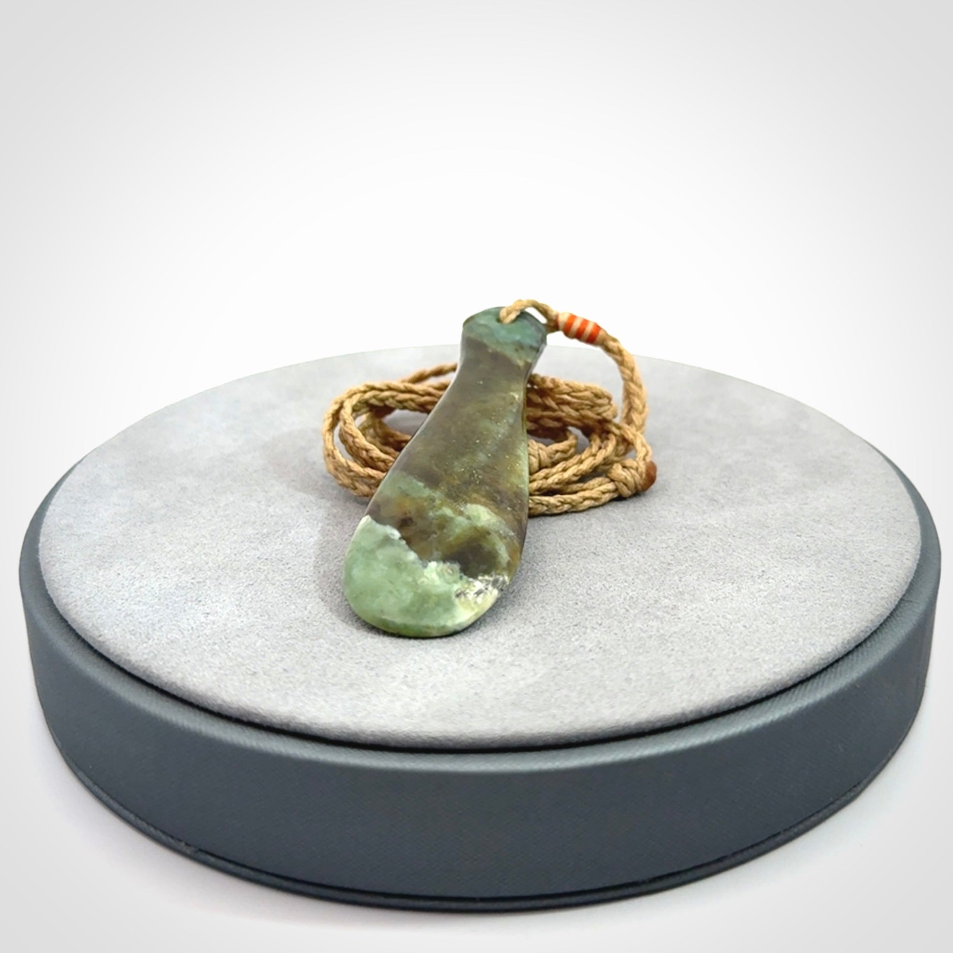 This is a sleek and slender hand carved New Zealand Jade mere pendant. The stone is a very beautiful green and the cord is tan and is adjustable. The pendant has a light polish and just glows. Provided in a woven kete pouch.
