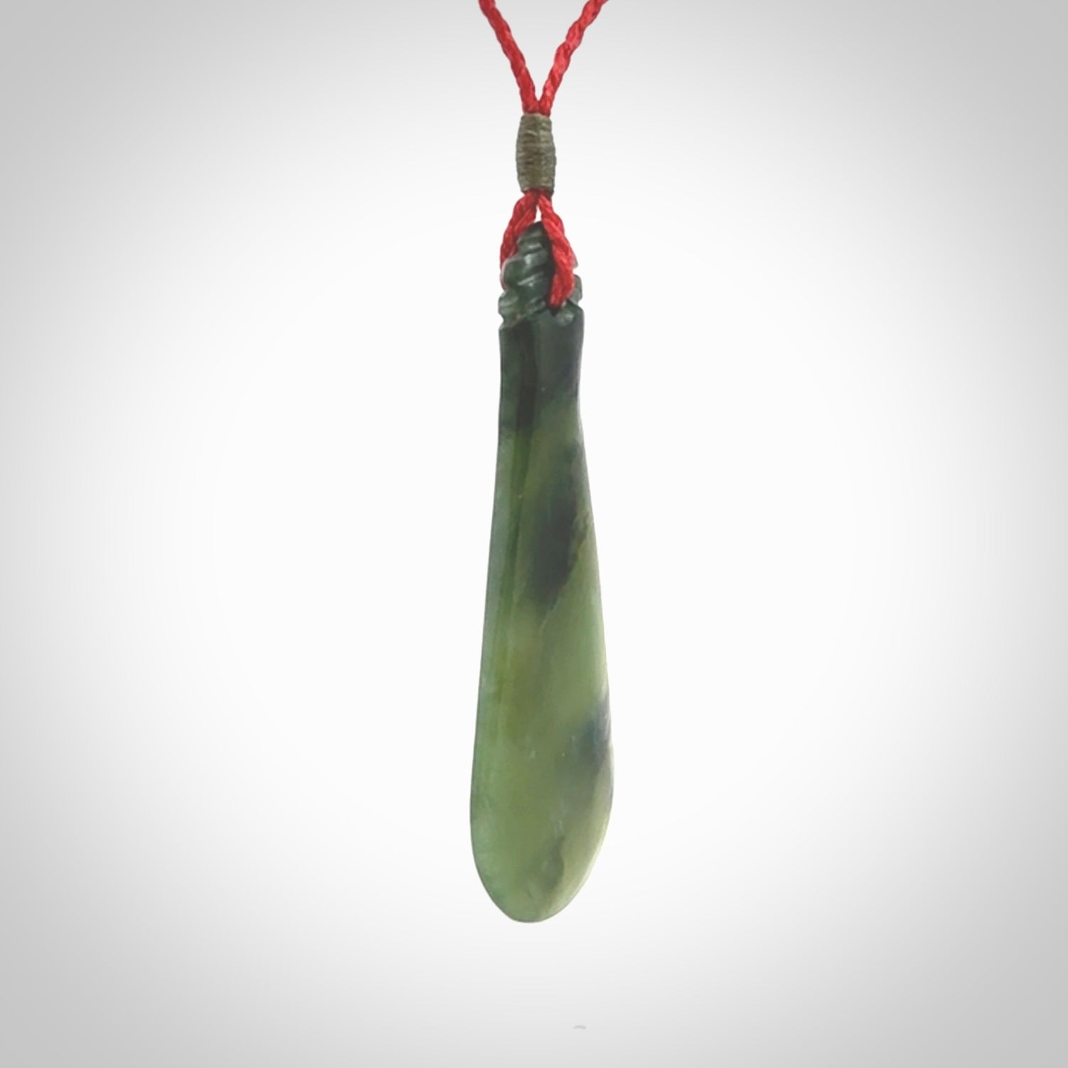 This is a sleek and slender hand carved New Zealand Jade mere pendant. The stone is a very beautiful green and the cord is either black, red or grey and is adjustable. The pendant has a light polish and just glows. Provided in a woven kete pouch.