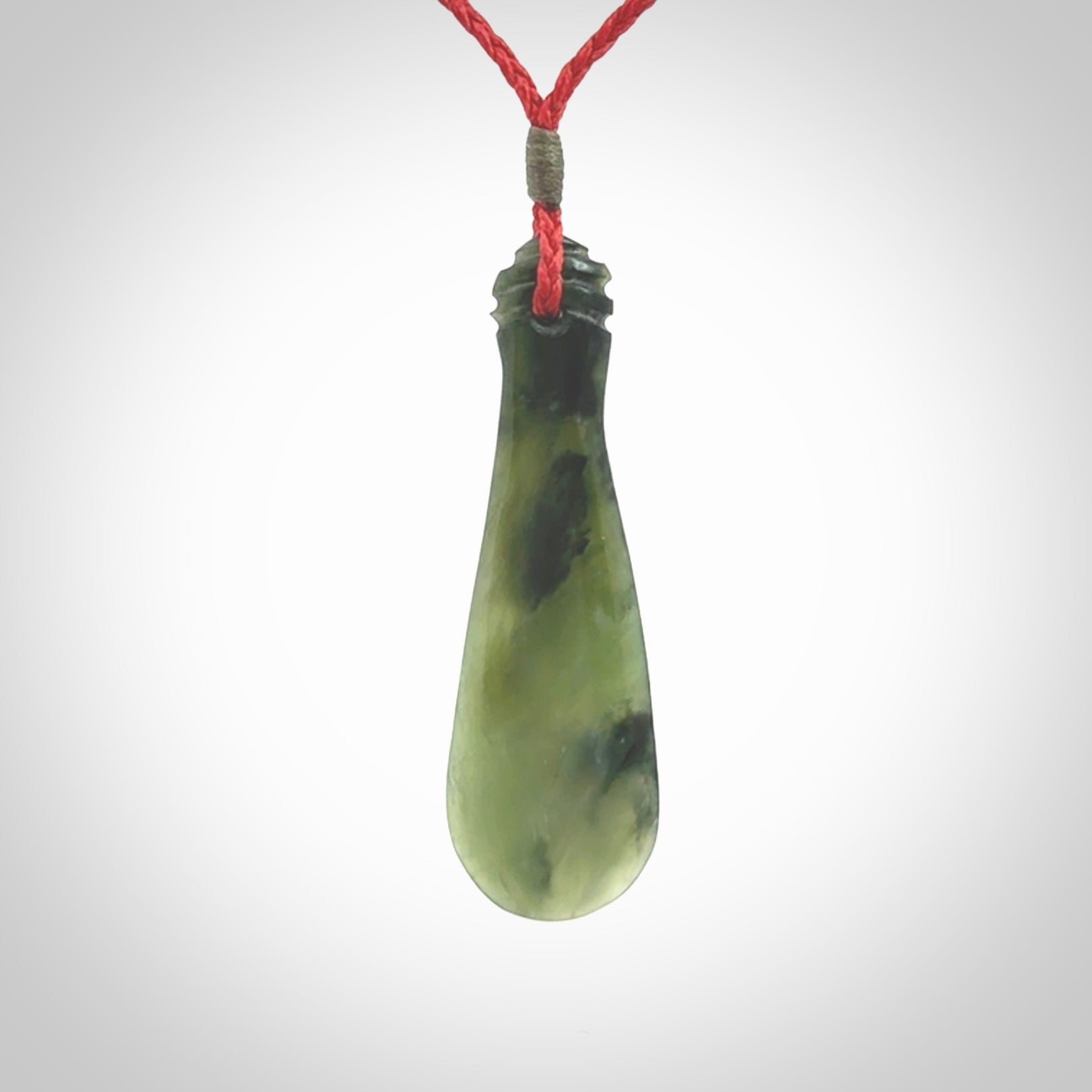 This is a sleek and slender hand carved New Zealand Jade mere pendant. The stone is a very beautiful green and the cord is either black, red or grey and is adjustable. The pendant has a light polish and just glows. Provided in a woven kete pouch.