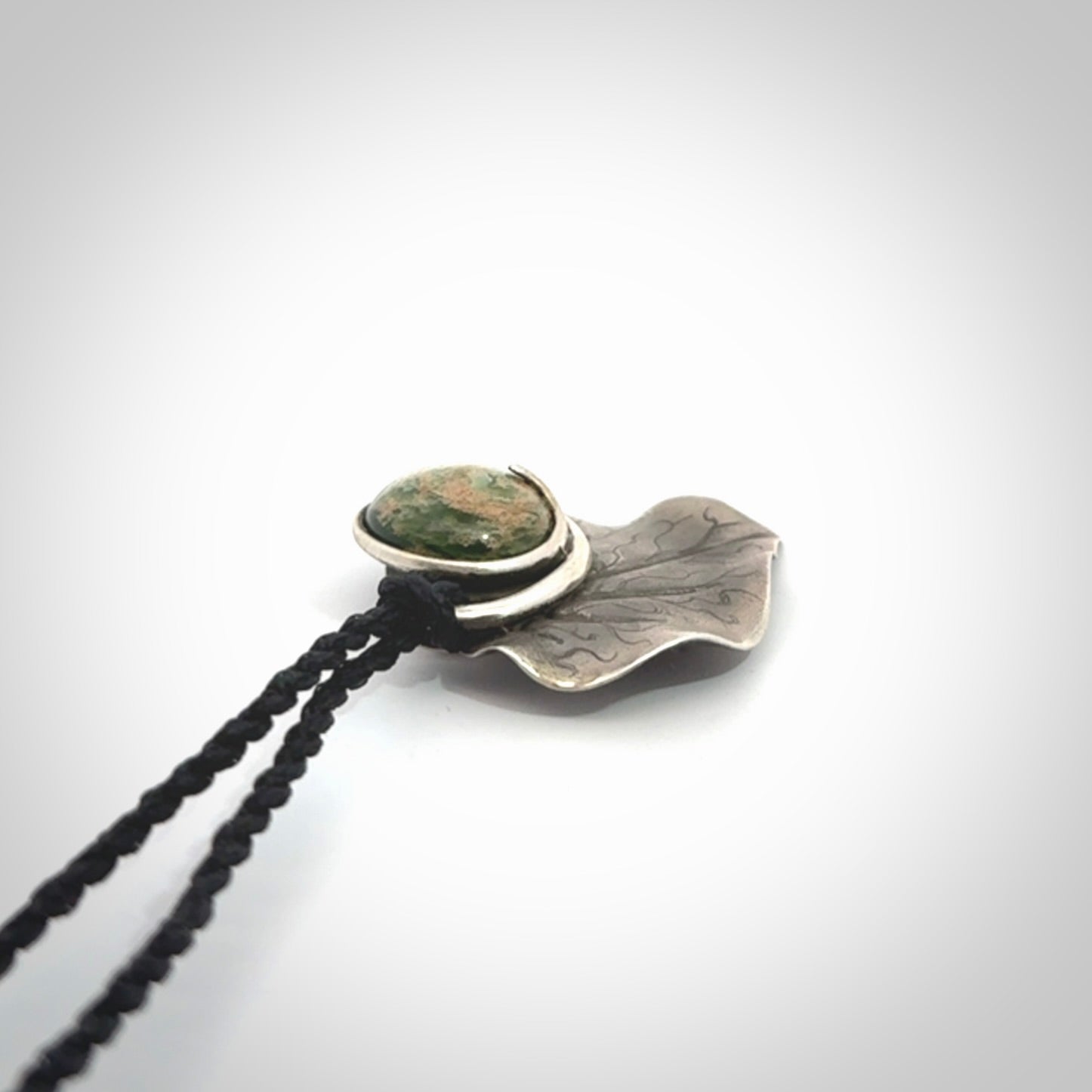 This is a hand carved Sterling Silver Kawakawa leaf pendant with New Zealand flower Jade insert. This is a medium sized necklace and is provided with an adjustable black cord.