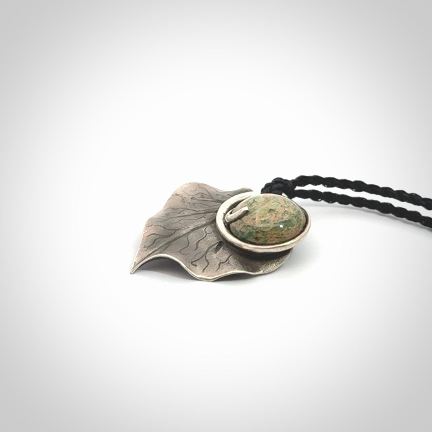 This is a hand carved Sterling Silver Kawakawa leaf pendant with New Zealand flower Jade insert. This is a medium sized necklace and is provided with an adjustable black cord.