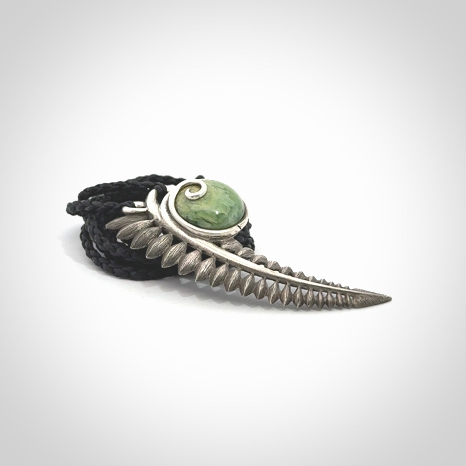 This is a hand carved Sterling Silver Fern leaf pendant with New Zealand flower Jade insert. This is a medium sized necklace and is provided with an adjustable black cord.