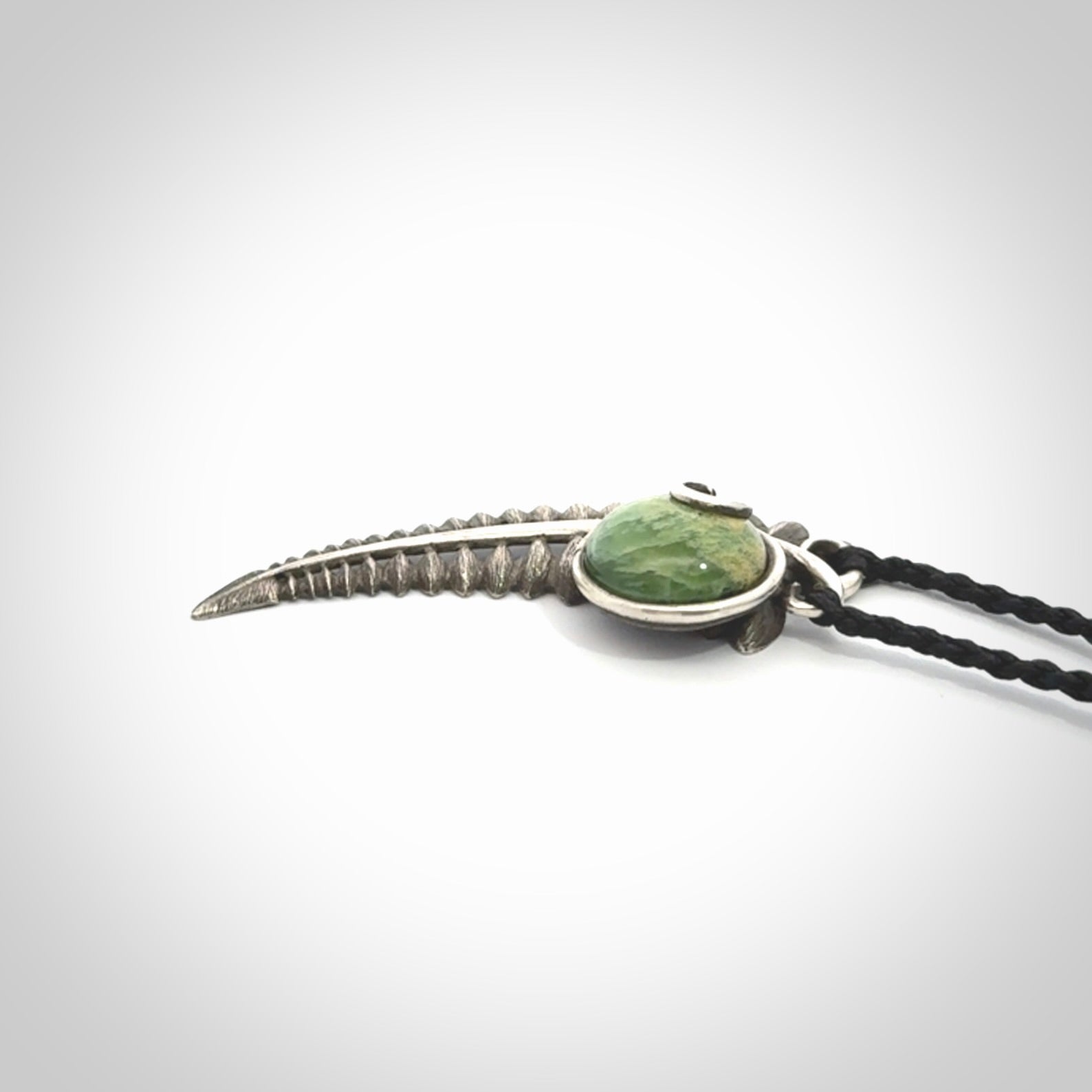 This is a hand carved Sterling Silver Fern leaf pendant with New Zealand flower Jade insert. This is a medium sized necklace and is provided with an adjustable black cord.