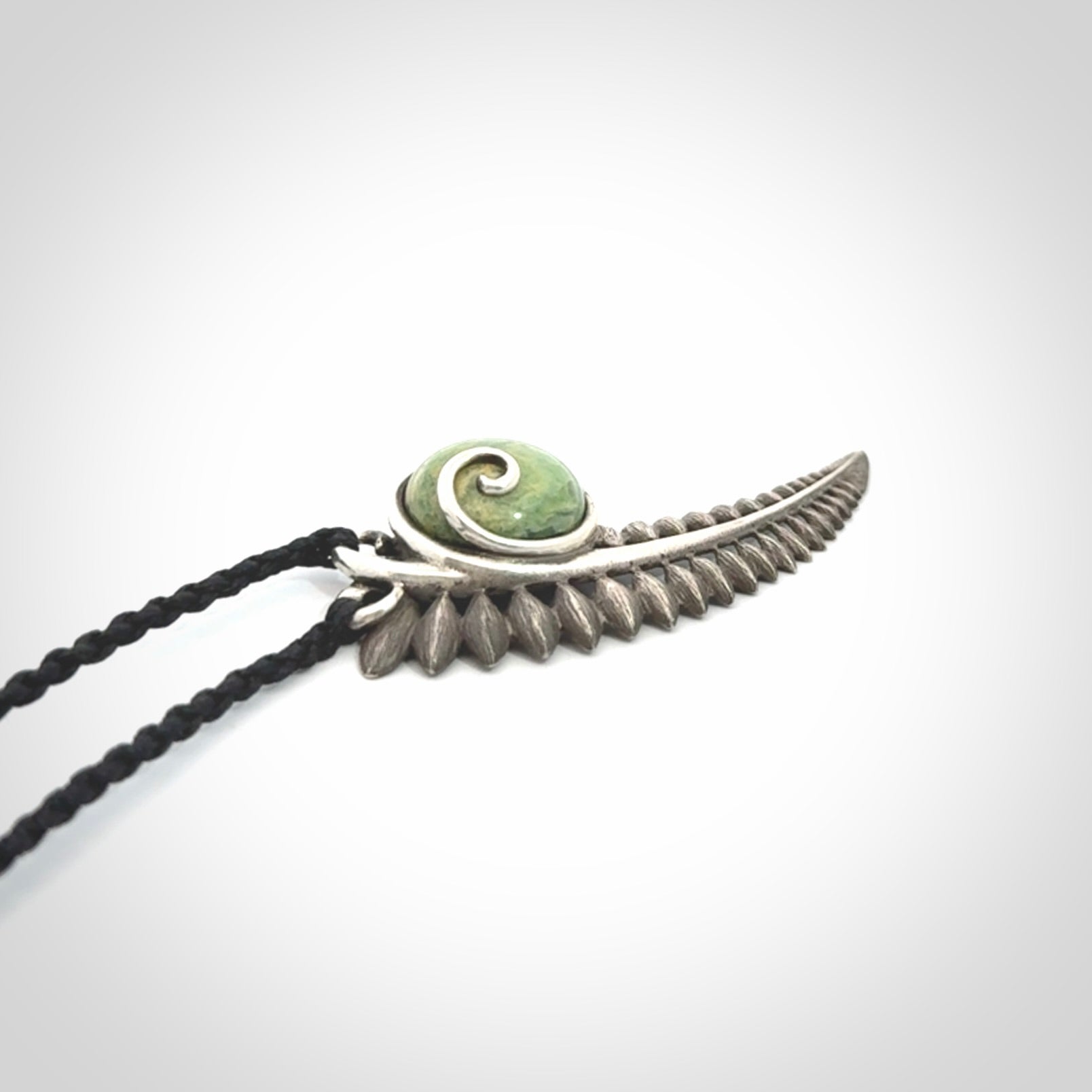 This is a hand carved Sterling Silver Fern leaf pendant with New Zealand flower Jade insert. This is a medium sized necklace and is provided with an adjustable black cord.