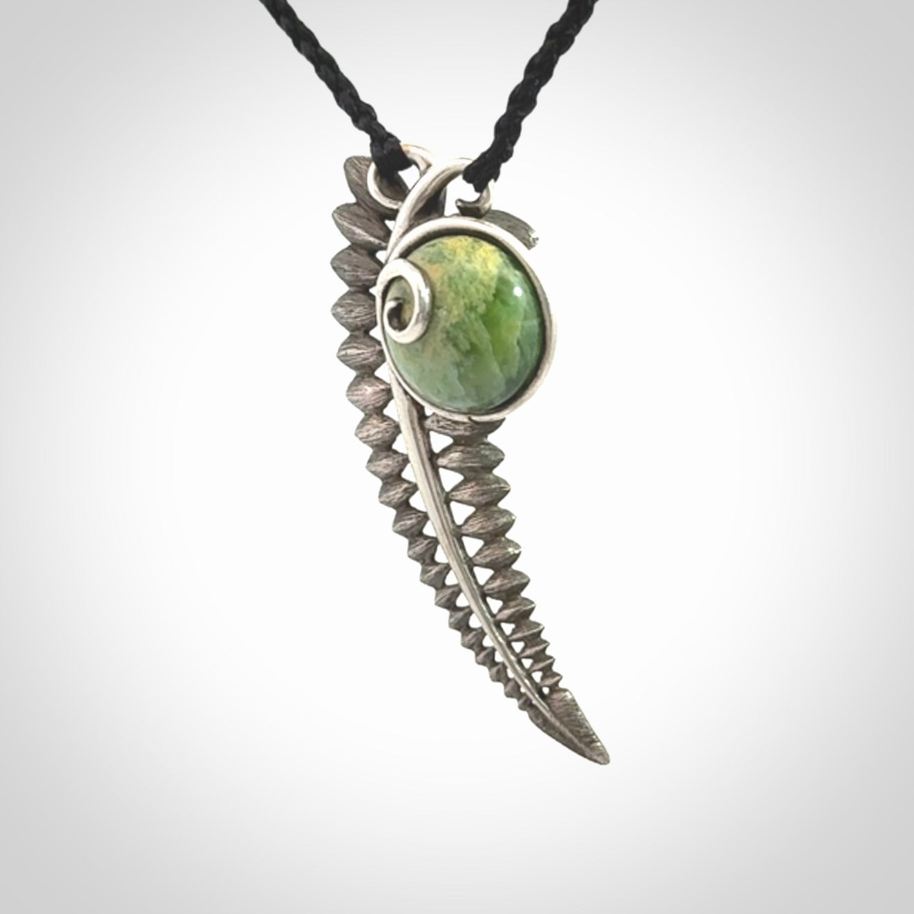 This is a hand carved Sterling Silver Fern leaf pendant with New Zealand flower Jade insert. This is a medium sized necklace and is provided with an adjustable black cord.