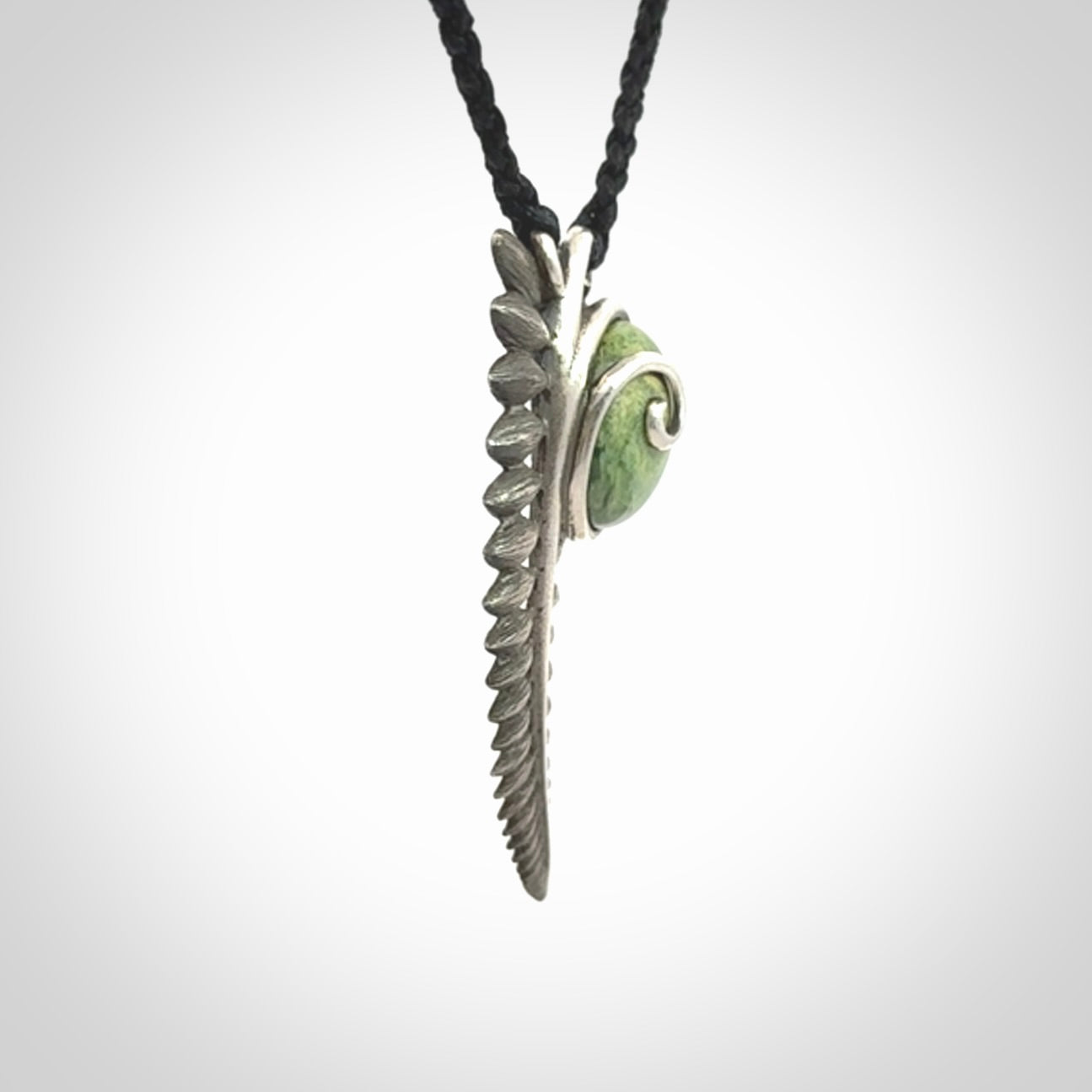 This is a hand carved Sterling Silver Fern leaf pendant with New Zealand flower Jade insert. This is a medium sized necklace and is provided with an adjustable black cord.