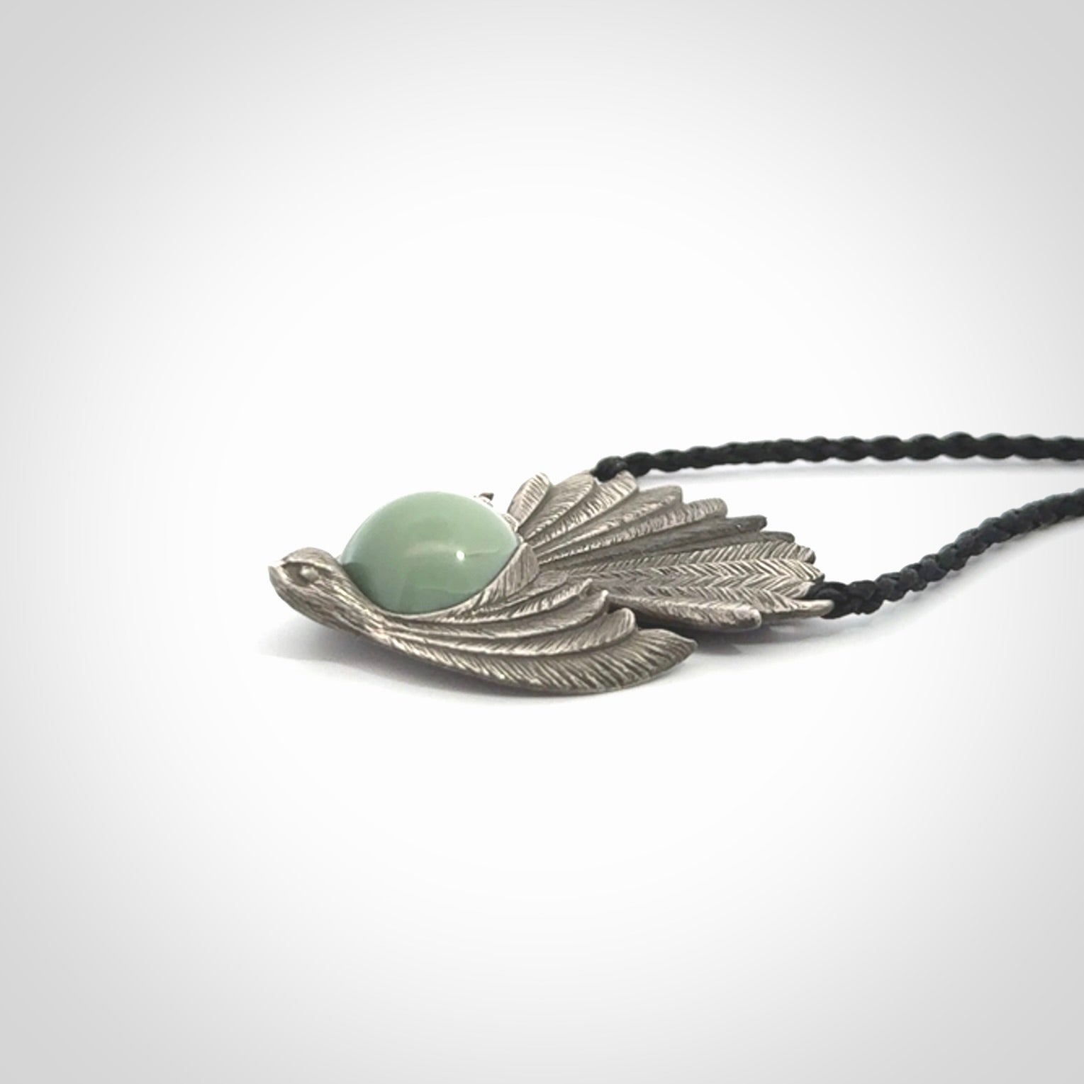 This is a hand carved Sterling Silver Fern fantail pendant with New Zealand Jade insert. This is a medium sized necklace and is provided with an adjustable black cord.