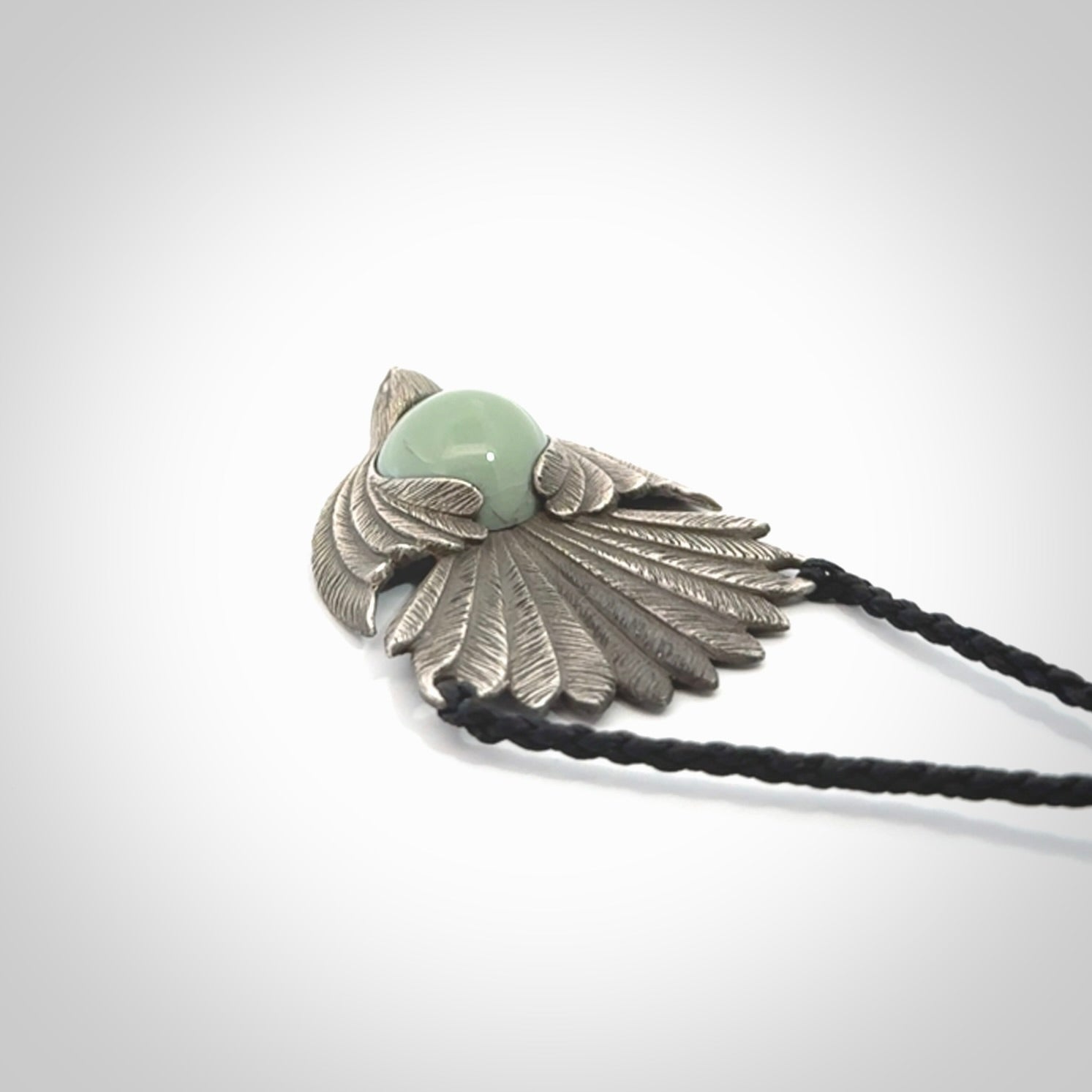 This is a hand carved Sterling Silver Fern fantail pendant with New Zealand Jade insert. This is a medium sized necklace and is provided with an adjustable black cord.