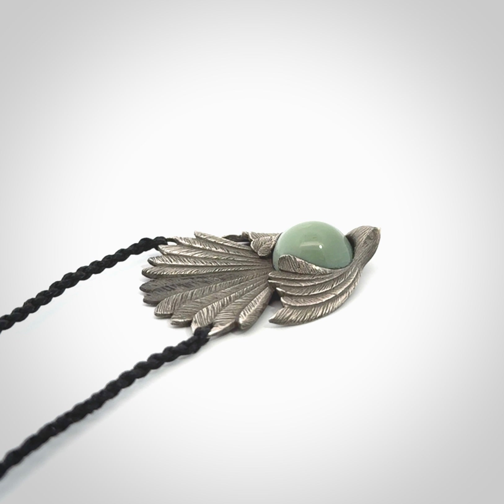 This is a hand carved Sterling Silver Fern fantail pendant with New Zealand Jade insert. This is a medium sized necklace and is provided with an adjustable black cord.