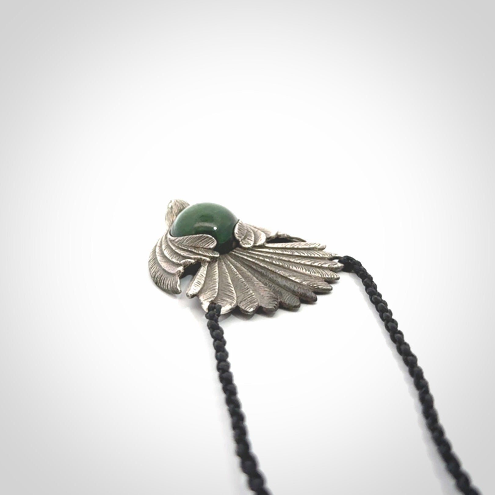 This is a hand carved Sterling Silver Fern fantail pendant with New Zealand Jade insert. This is a medium sized necklace and is provided with an adjustable black cord.