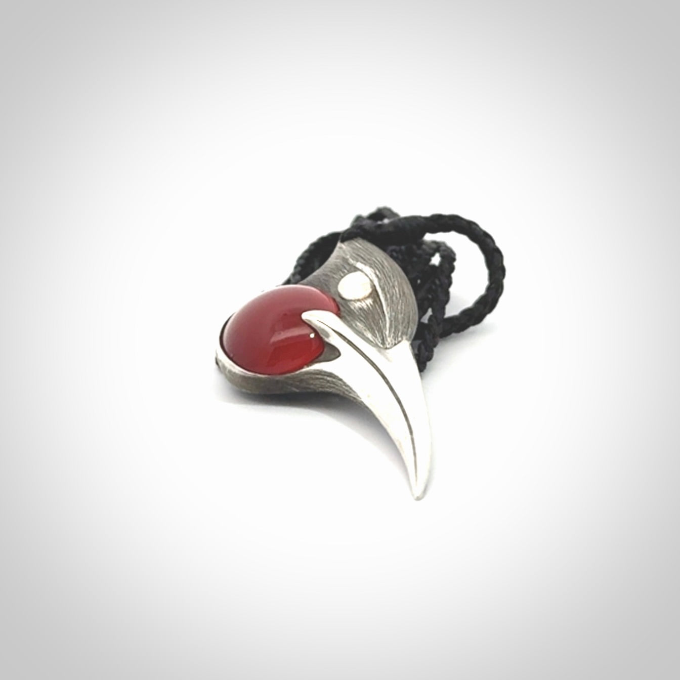 This is a hand carved Sterling Silver Huia bird pendant with Red Cats Eye insert. This is a medium sized necklace and is provided with an adjustable black cord.