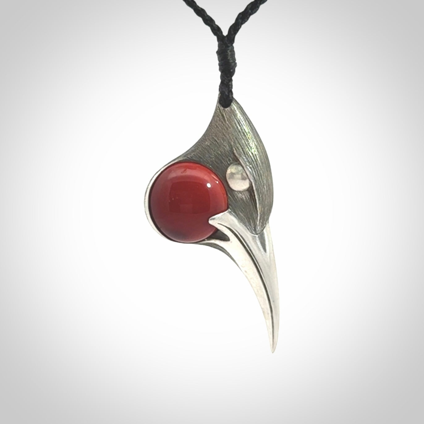 This is a hand carved Sterling Silver Huia bird pendant with Red Cats Eye insert. This is a medium sized necklace and is provided with an adjustable black cord.