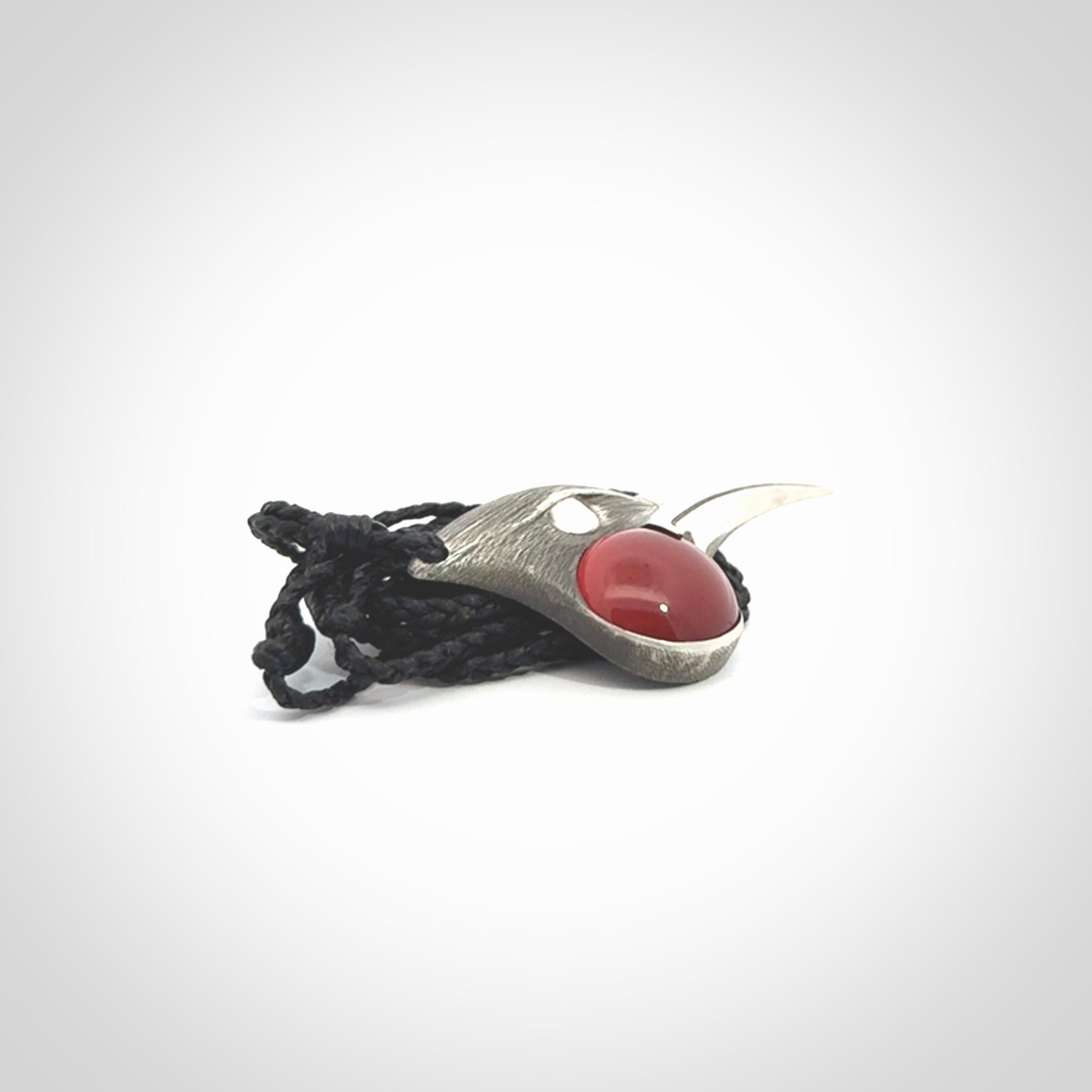 This is a hand carved Sterling Silver Huia bird pendant with Red Cats Eye insert. This is a medium sized necklace and is provided with an adjustable black cord.