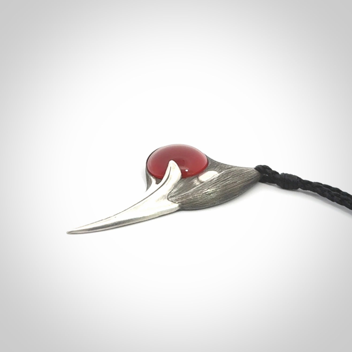This is a hand carved Sterling Silver Huia bird pendant with Red Cats Eye insert. This is a medium sized necklace and is provided with an adjustable black cord.