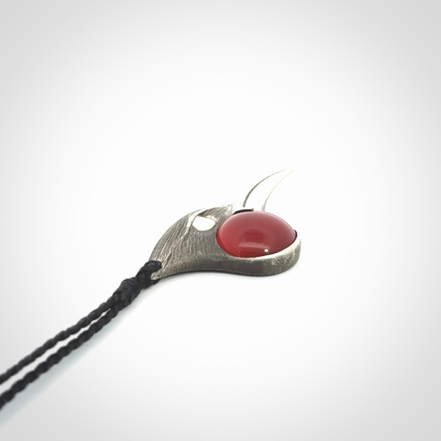 This is a hand carved Sterling Silver Huia bird pendant with Red Cats Eye insert. This is a medium sized necklace and is provided with an adjustable black cord.