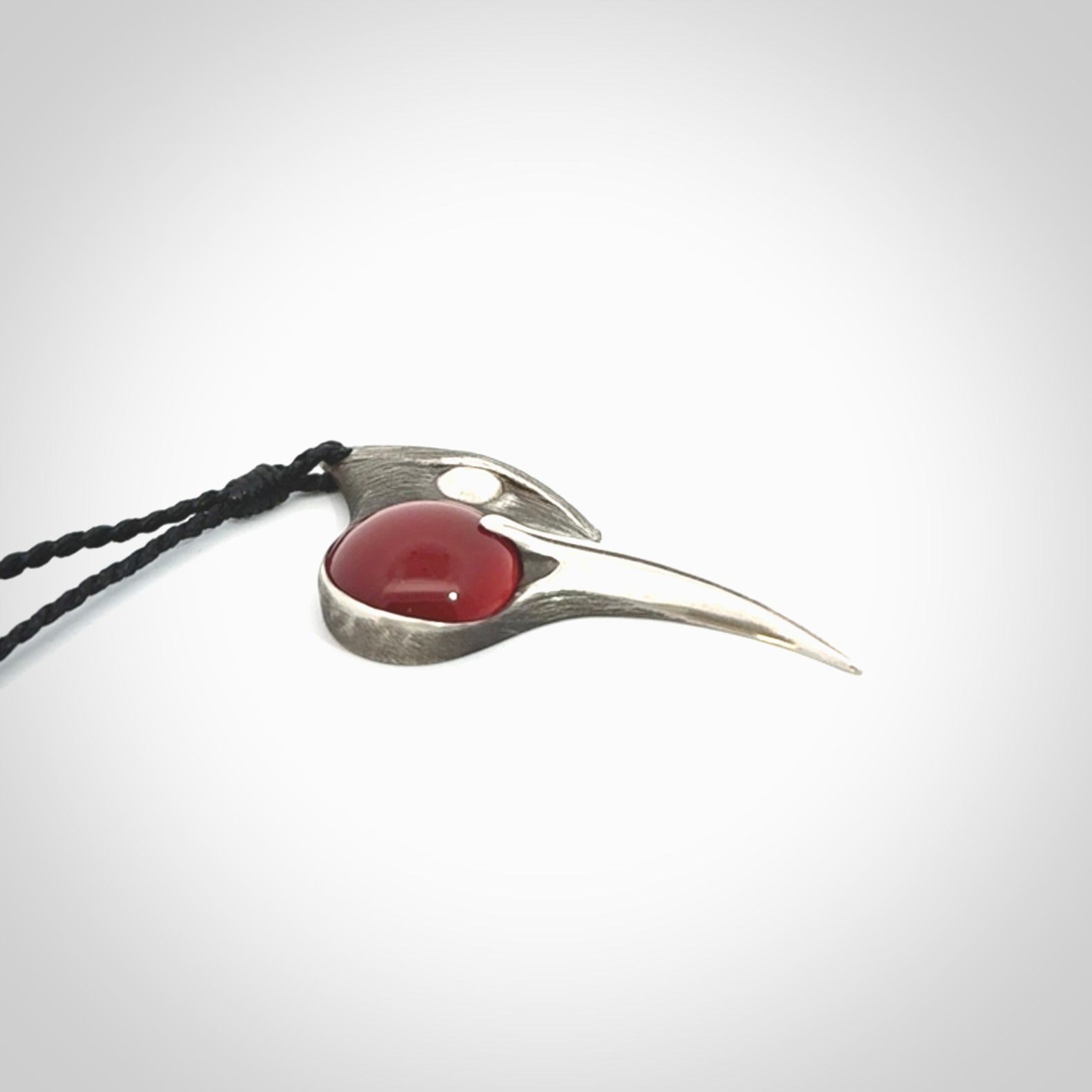 This is a hand carved Sterling Silver Huia bird pendant with Red Cats Eye insert. This is a medium sized necklace and is provided with an adjustable black cord.