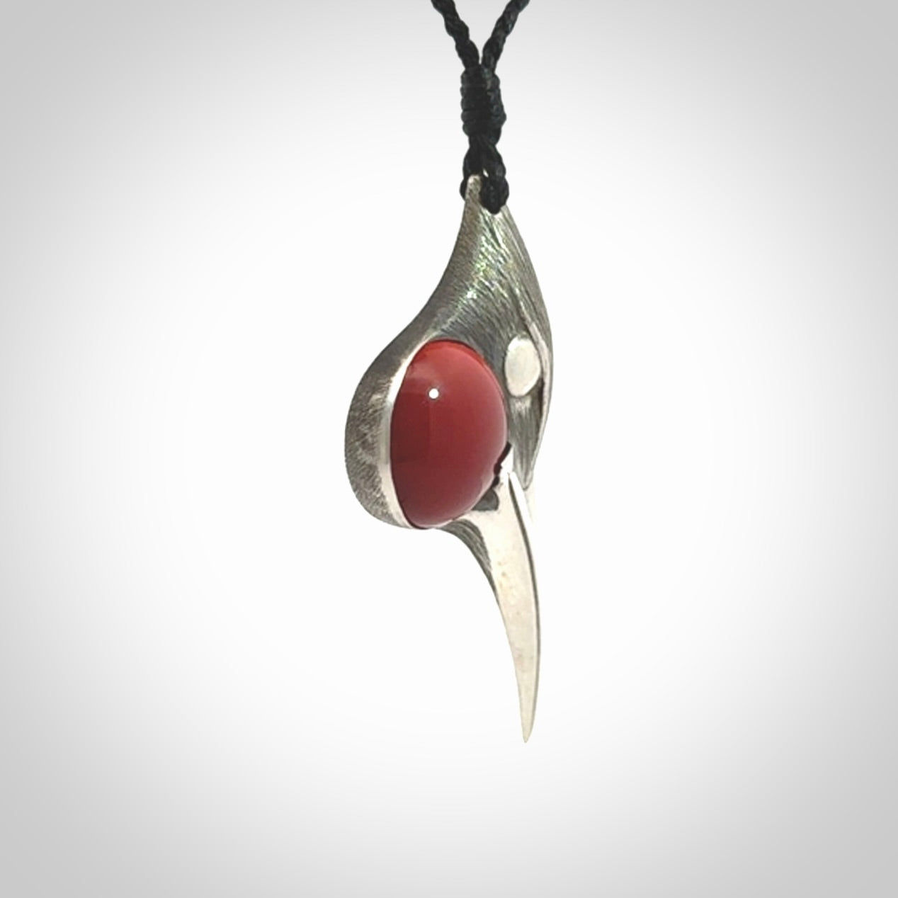 This is a hand carved Sterling Silver Huia bird pendant with Red Cats Eye insert. This is a medium sized necklace and is provided with an adjustable black cord.