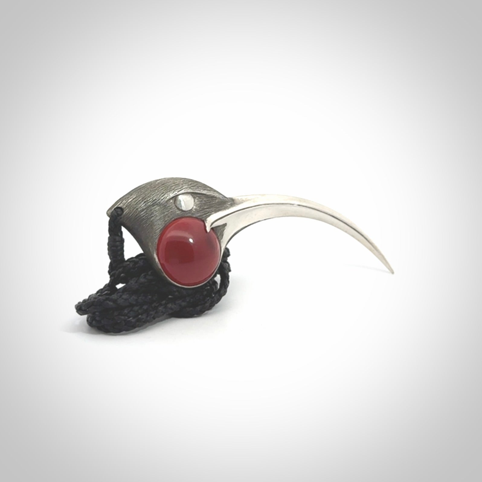 This is a hand carved Sterling Silver Huia bird pendant with Red Cats Eye insert. This is a large sized necklace and is provided with an adjustable black cord.