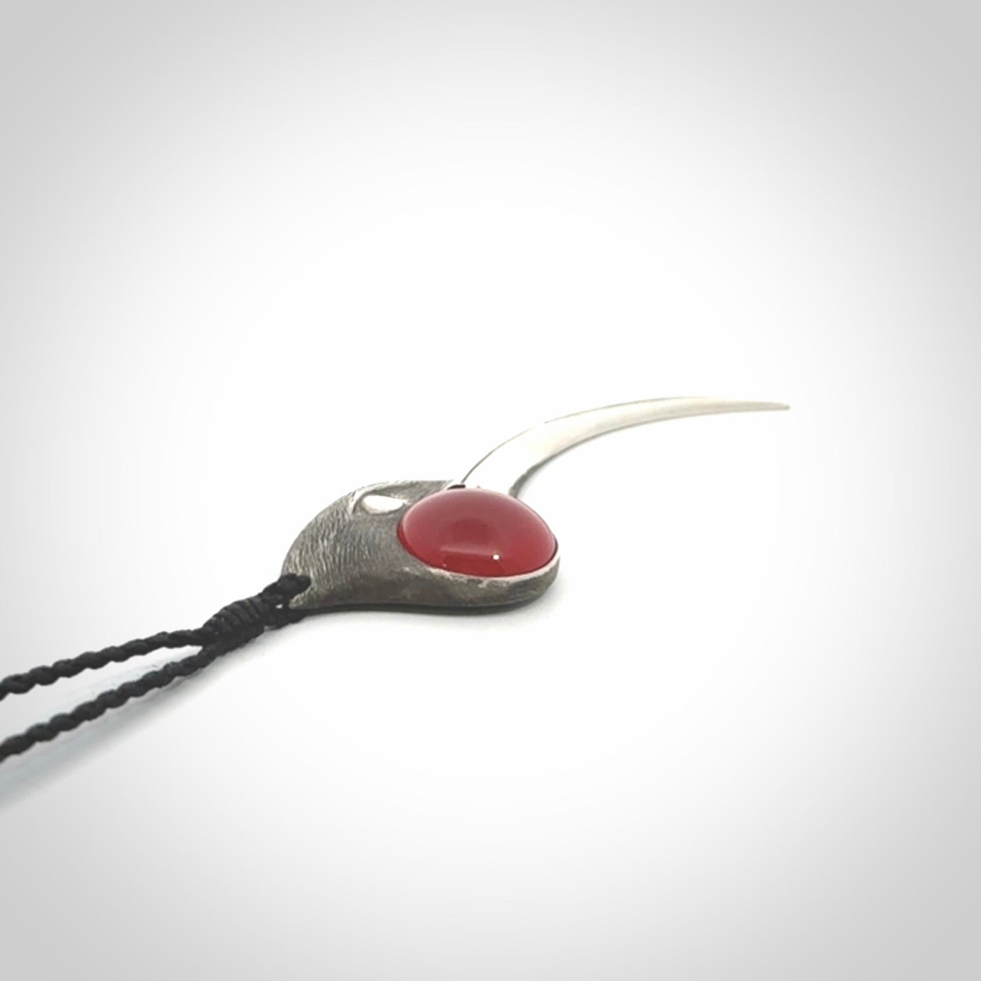 This is a hand carved Sterling Silver Huia bird pendant with Red Cats Eye insert. This is a large sized necklace and is provided with an adjustable black cord.
