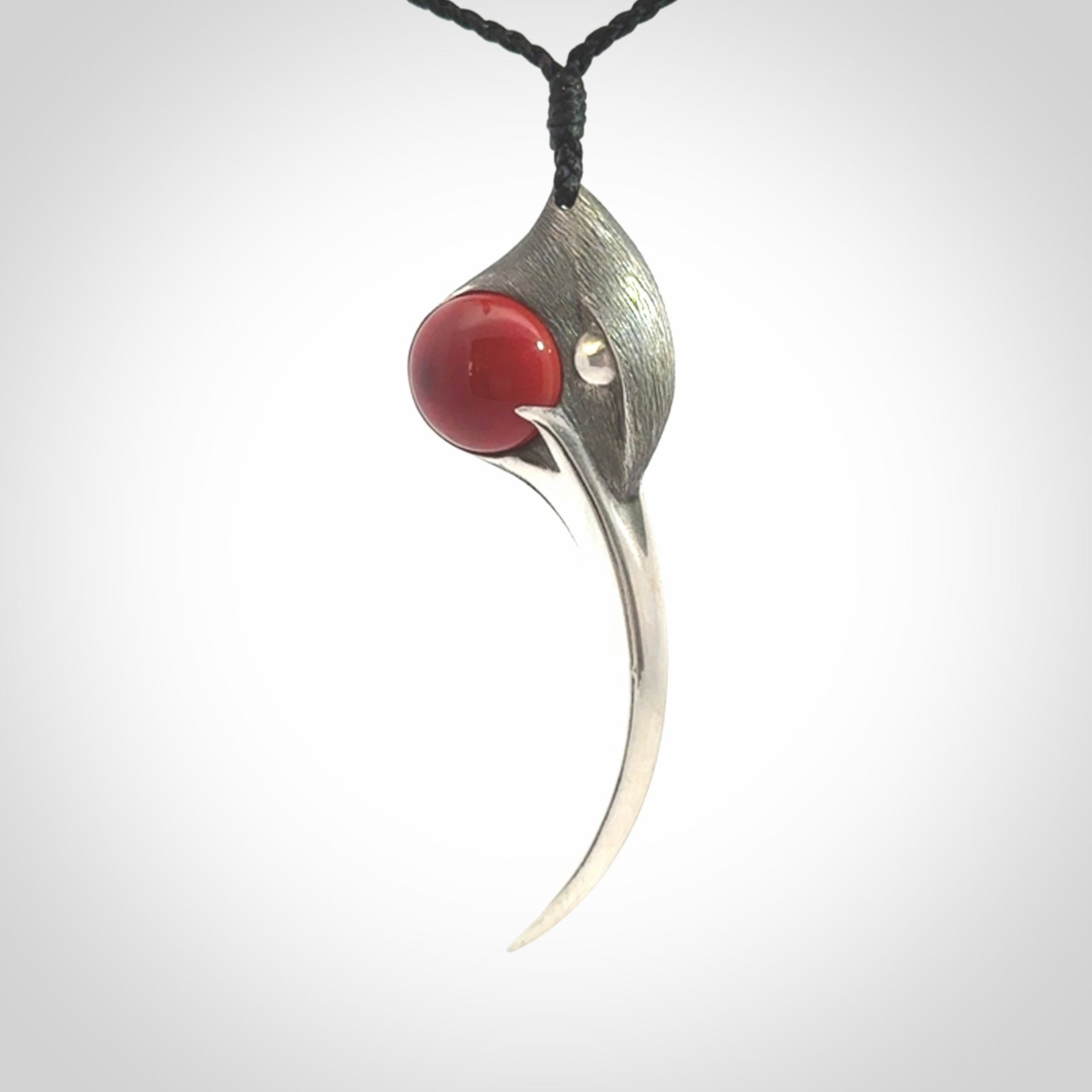 This is a hand carved Sterling Silver Huia bird pendant with Red Cats Eye insert. This is a large sized necklace and is provided with an adjustable black cord.