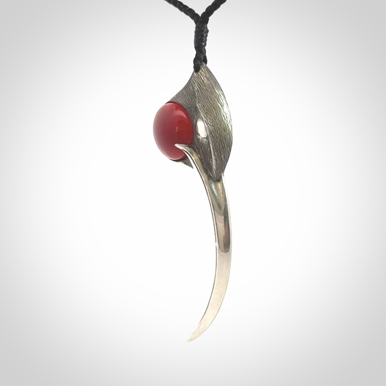 This is a hand carved Sterling Silver Huia bird pendant with Red Cats Eye insert. This is a large sized necklace and is provided with an adjustable black cord.