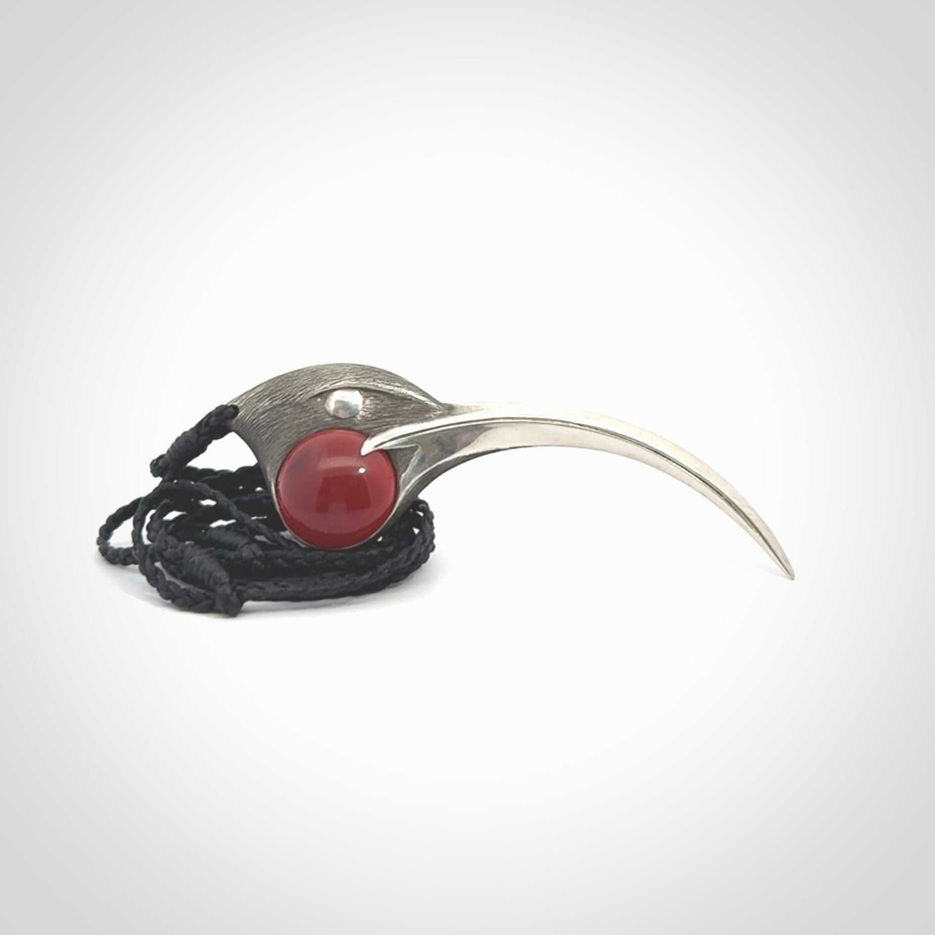 This is a hand carved Sterling Silver Huia bird pendant with Red Cats Eye insert. This is a large sized necklace and is provided with an adjustable black cord.